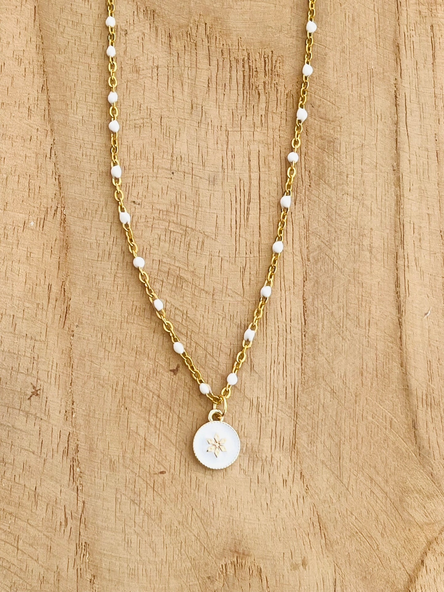 Collier fantaisie en acier inoxydable doré et résine époxy blanc.
Pendentif rond avec une fleur.
Bijou fantaisie fait main.