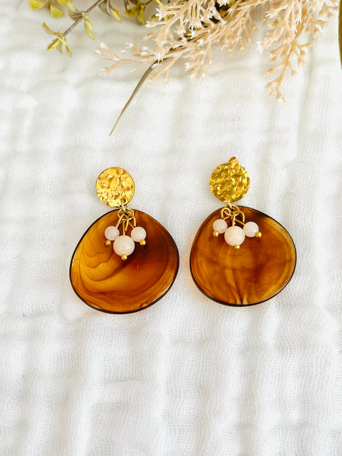 Boucles d'oreilles fantaisie fait main.
Clous d'oreilles ronds martelés en acier inox doré, pendentifs forme pétale en acrylique marron, perles de jade nude.
Bijou fait main.