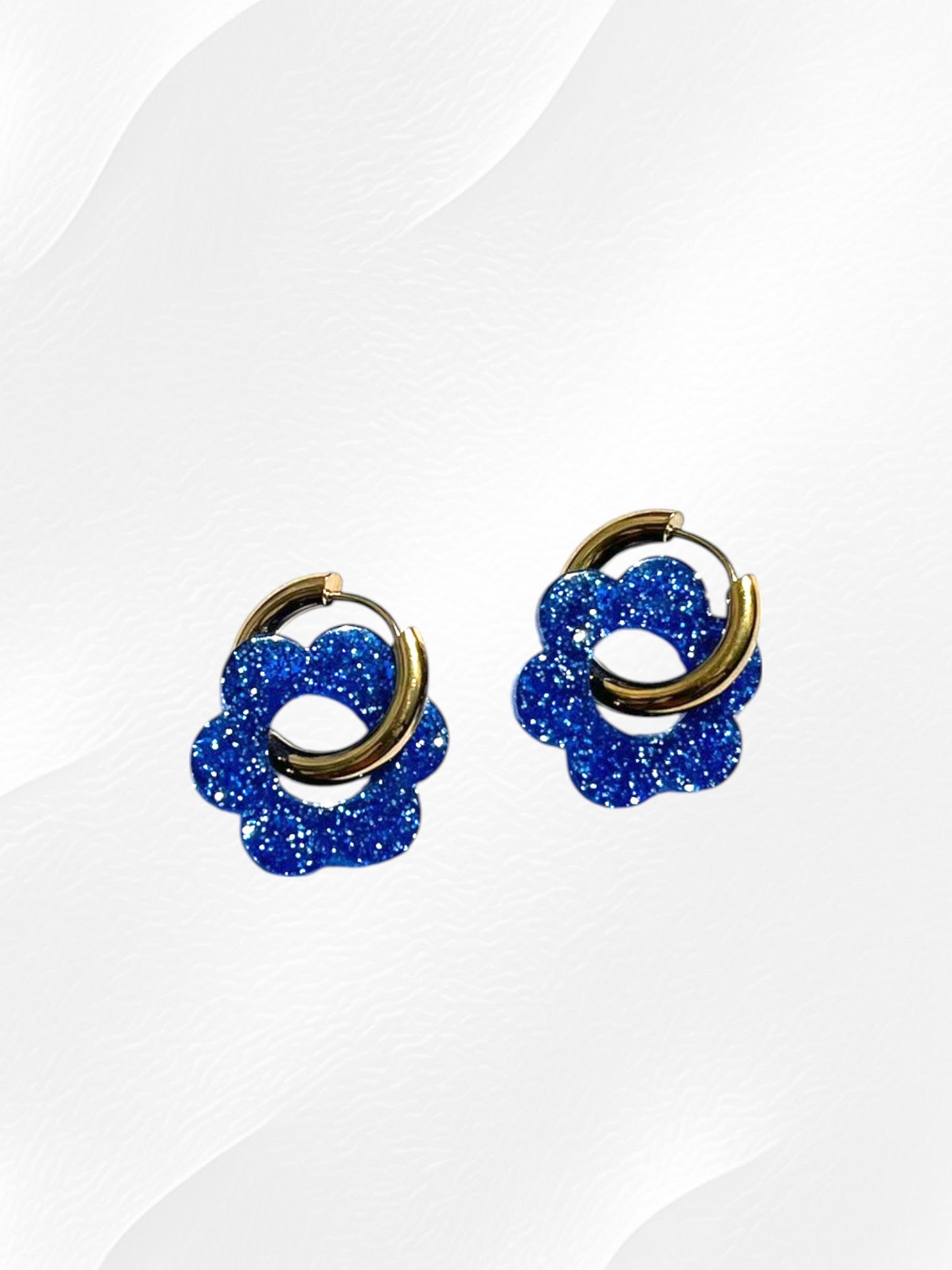 Boucles d'oreilles créoles adaptées pour les enfants à partir de 6 ans.
Créoles en acier inoxydable doré de 15mm.
Petites fleurs bleu pailleté en acrylique.