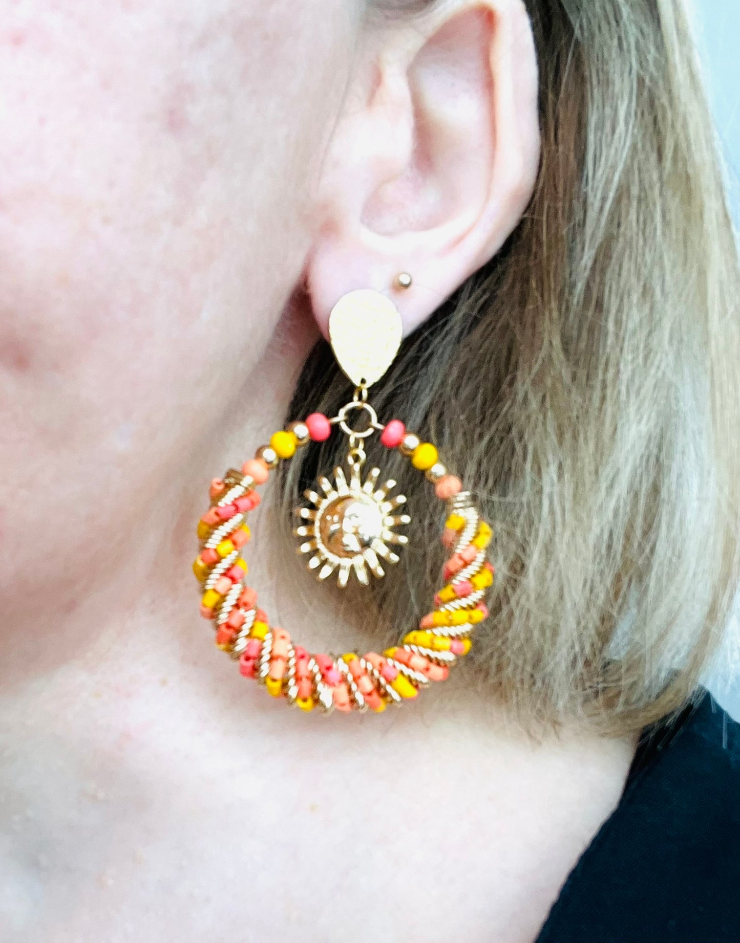 Boucles d'oreilles fantaisie fait main.
Clous d'oreilles goutte en acier doré.
Grand pendentif rond en perles de rocaille jaune, corail, rouge, orange.
Breloque soleil en laiton plaqué or 18k.
Bijou fait main.