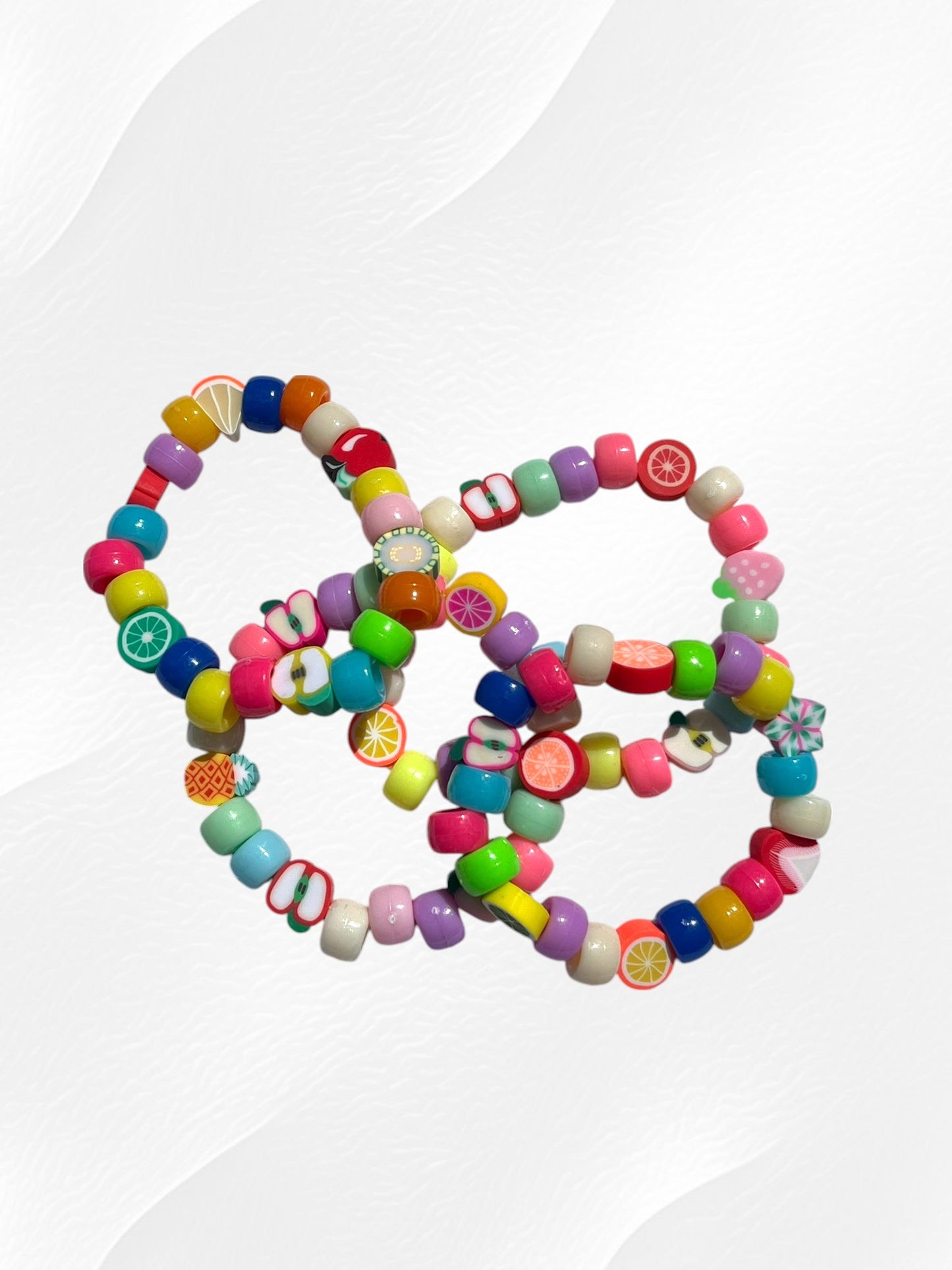 Bracelet pour enfant monté sur élastique.
Perles en acrylique multicolores fluo et perles fruits en argile polymère.