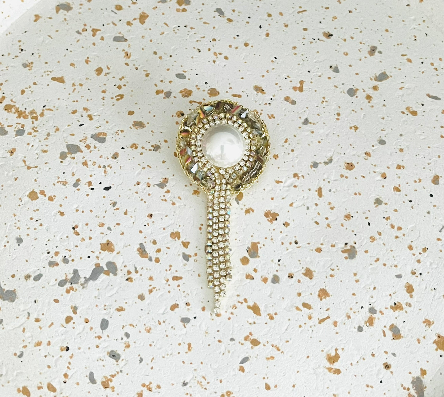 Broche fantaisie ronde grise et blanc nacré, franges de strass
