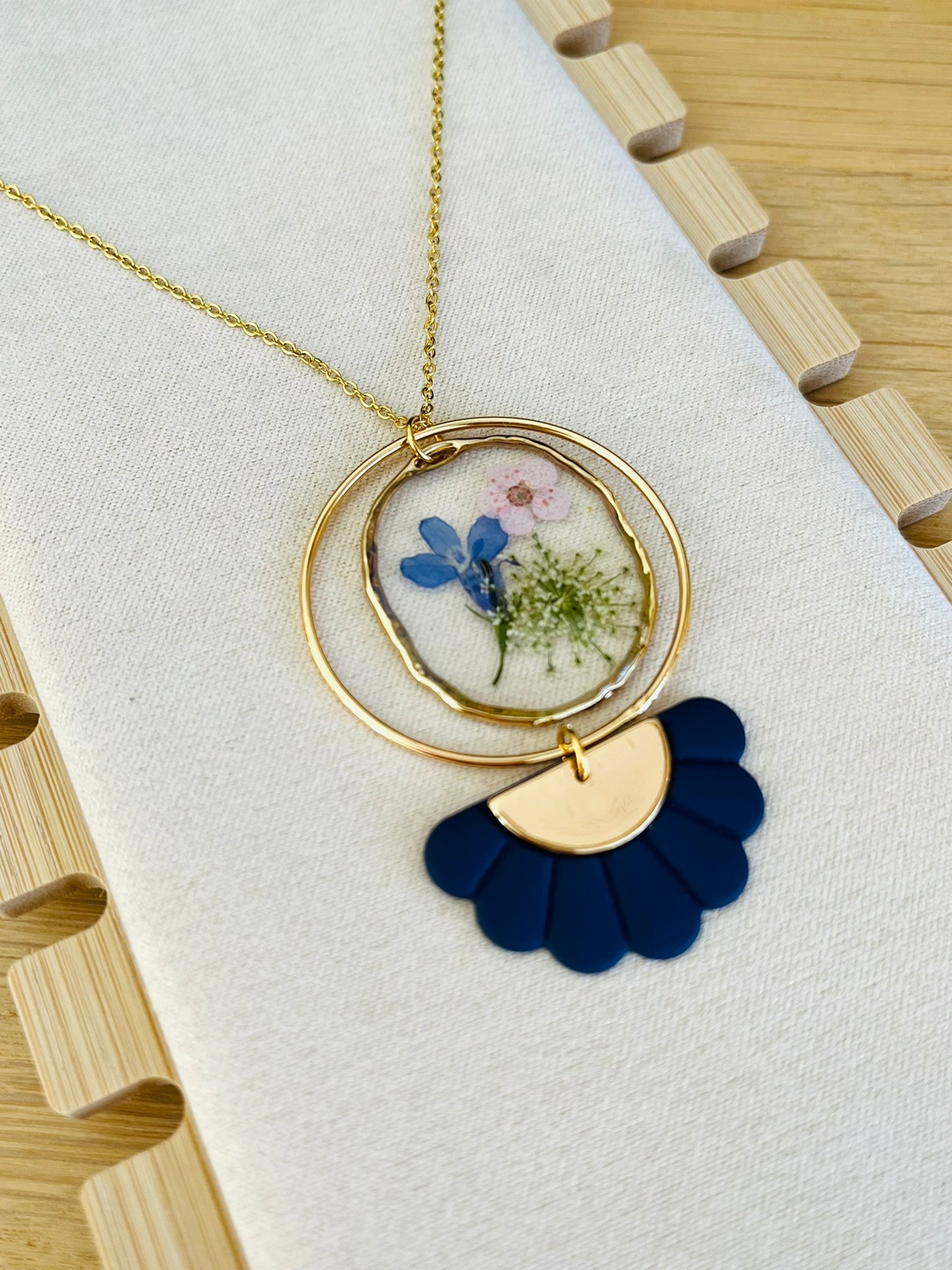 Collier fantaisie fait main.
Chaine fine en acier inoxydable doré; pendentif rond en résine avec fleurs séchées rose; pendentif demi-fleur bleu marine.
Bijou fantaisie fait main.