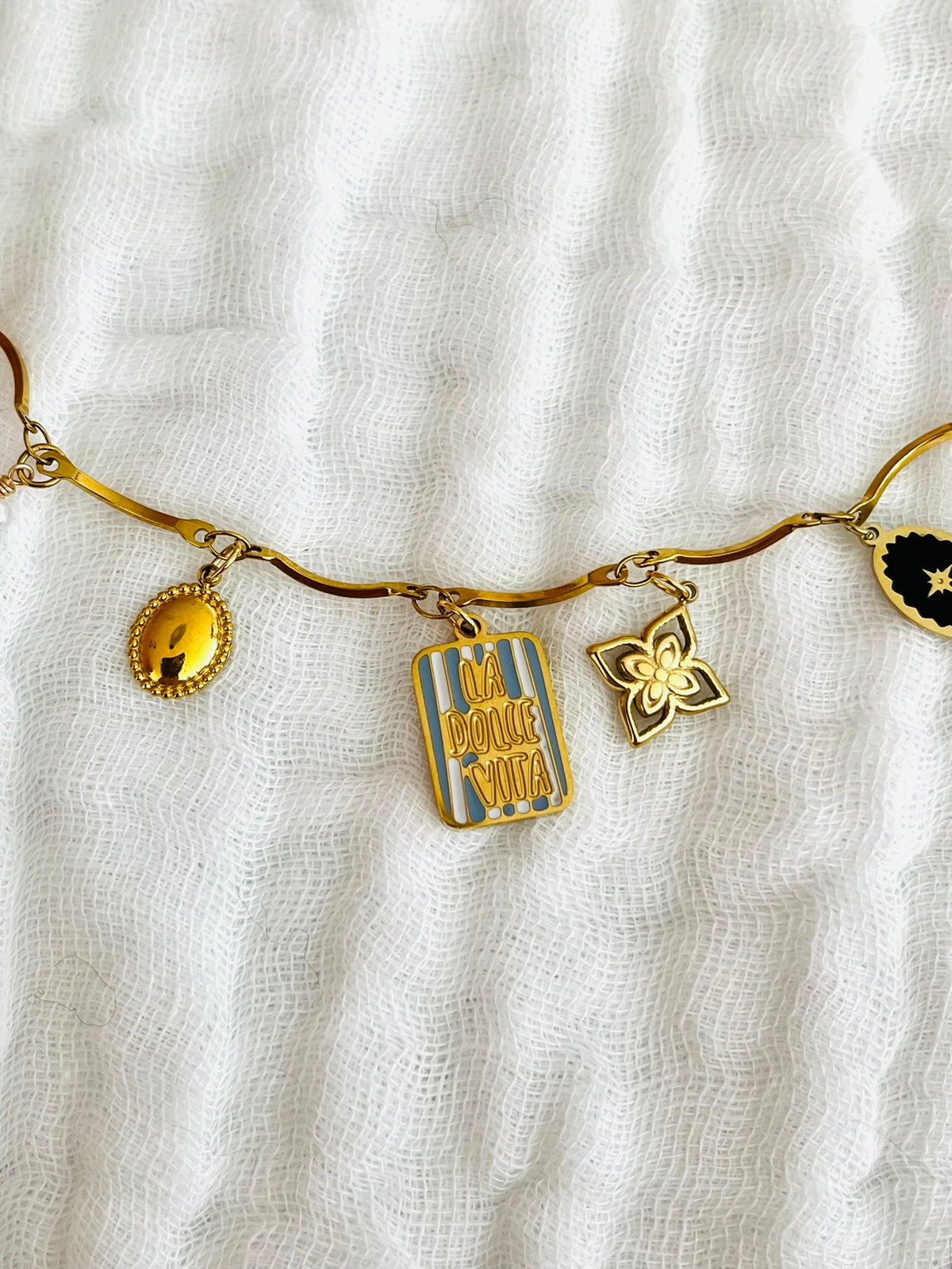 Collier fantaisie fait main.
Collier en acier inoxydable avec pampilles en nacre. Fleur, étoile, trèfle, limule en acier doré.
Pendentif central rectangle rayé rouge et rose gravé "Ciao Bella"