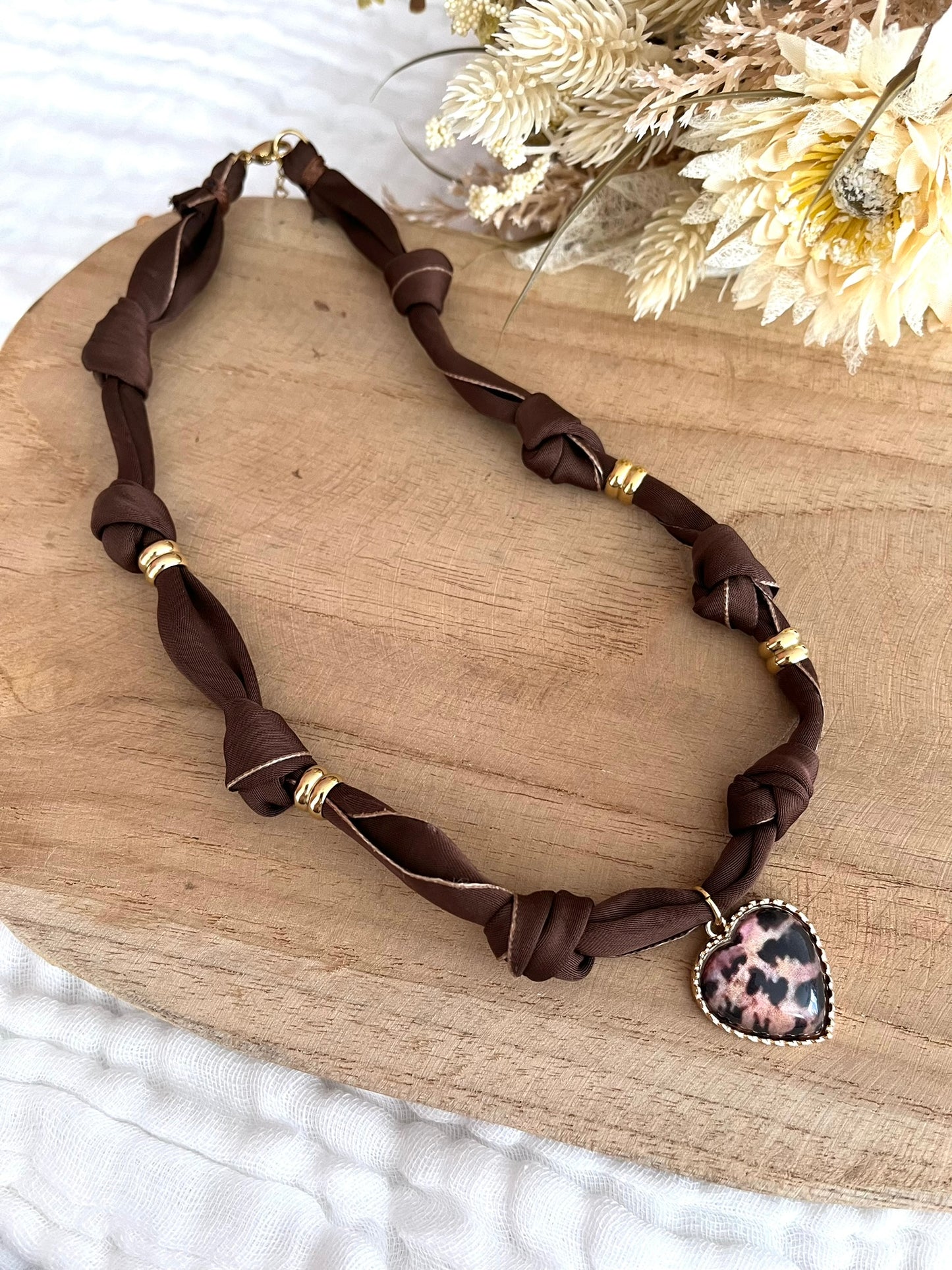 Collier en tissu marron et pendentif coeur imprimé léopard
Tissu satiné et pendentif en métal doré.
Longueur: 44cm + 5cm
Bijou fantaisie fait main.