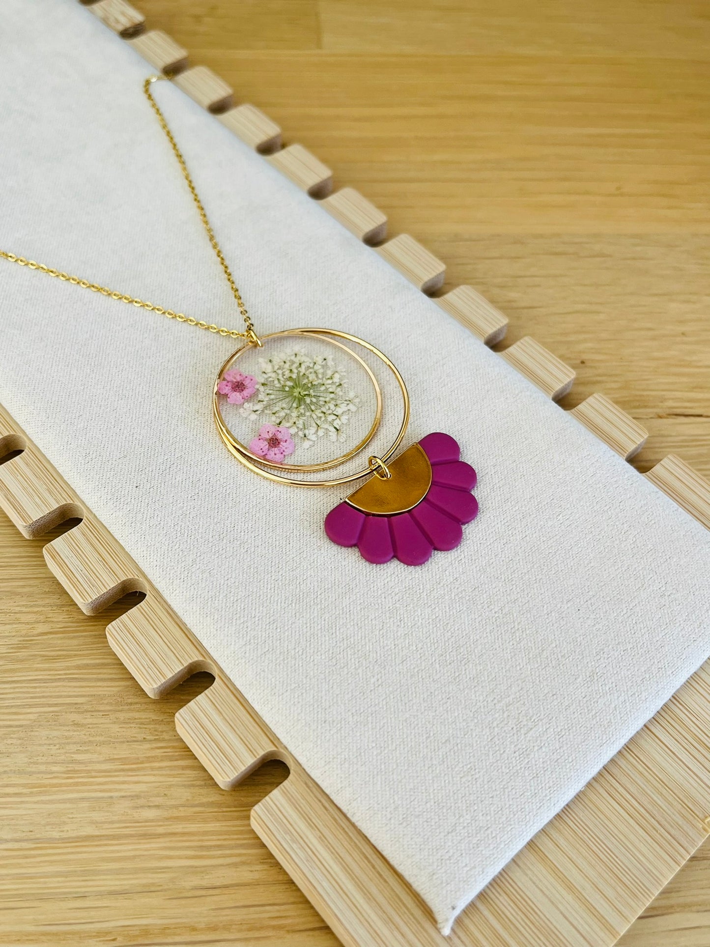 Chaine fine en acier inoxydable doré; pendentif rond en résine avec fleurs séchées rose; pendentif demi-fleur rose framboise.
Bijou fantaisie fait main.