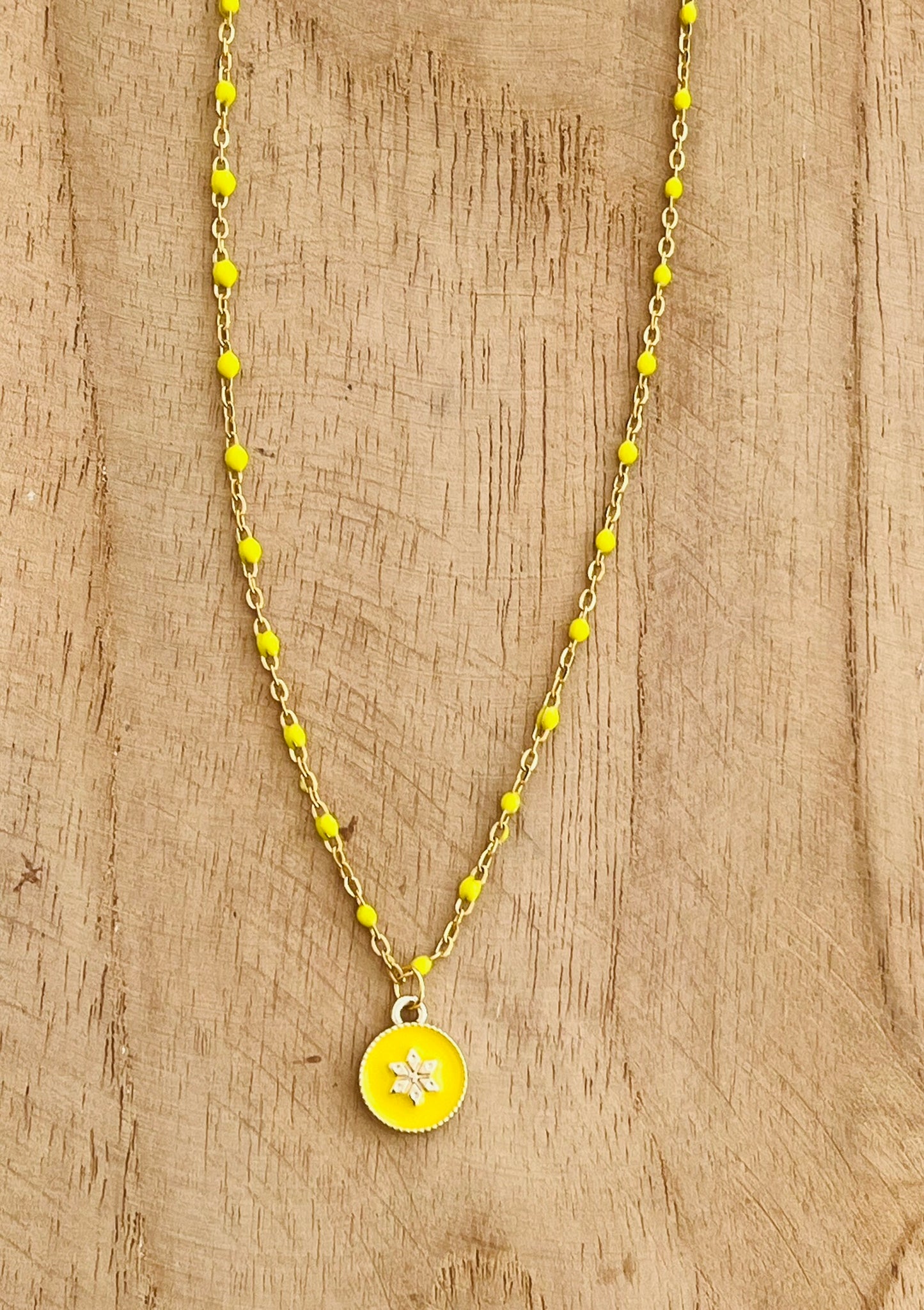 Collier fantaisie en acier inoxydable doré et résine époxy jaune.
Pendentif rond avec une fleur.
Bijou fantaisie fait main.