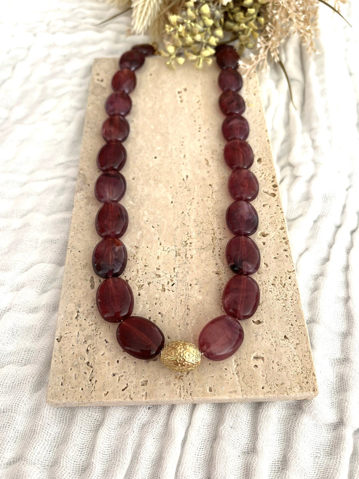 Collier fantaisie fait main.
Collier de perles ovales en résine aubergine marbré.
Perle centrale ouvragée en acier inoxydable doré.
Bijou fantaisie fait main