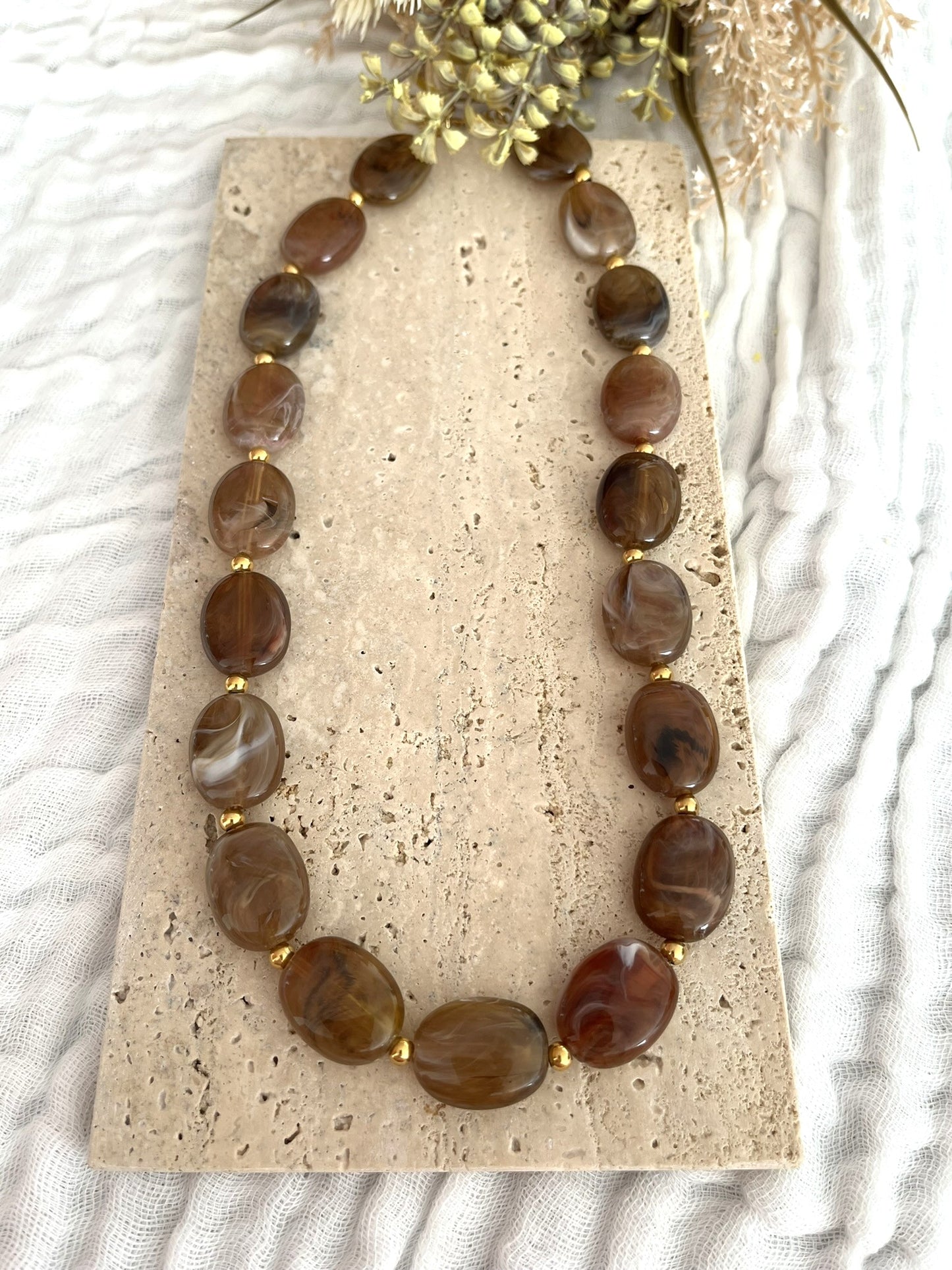 Collier fantaisie fait main.
Perles ovales en résine marron marbré.
Petites perles intercalaires ronde en acier doré.
Bijou fantaisie fait main.