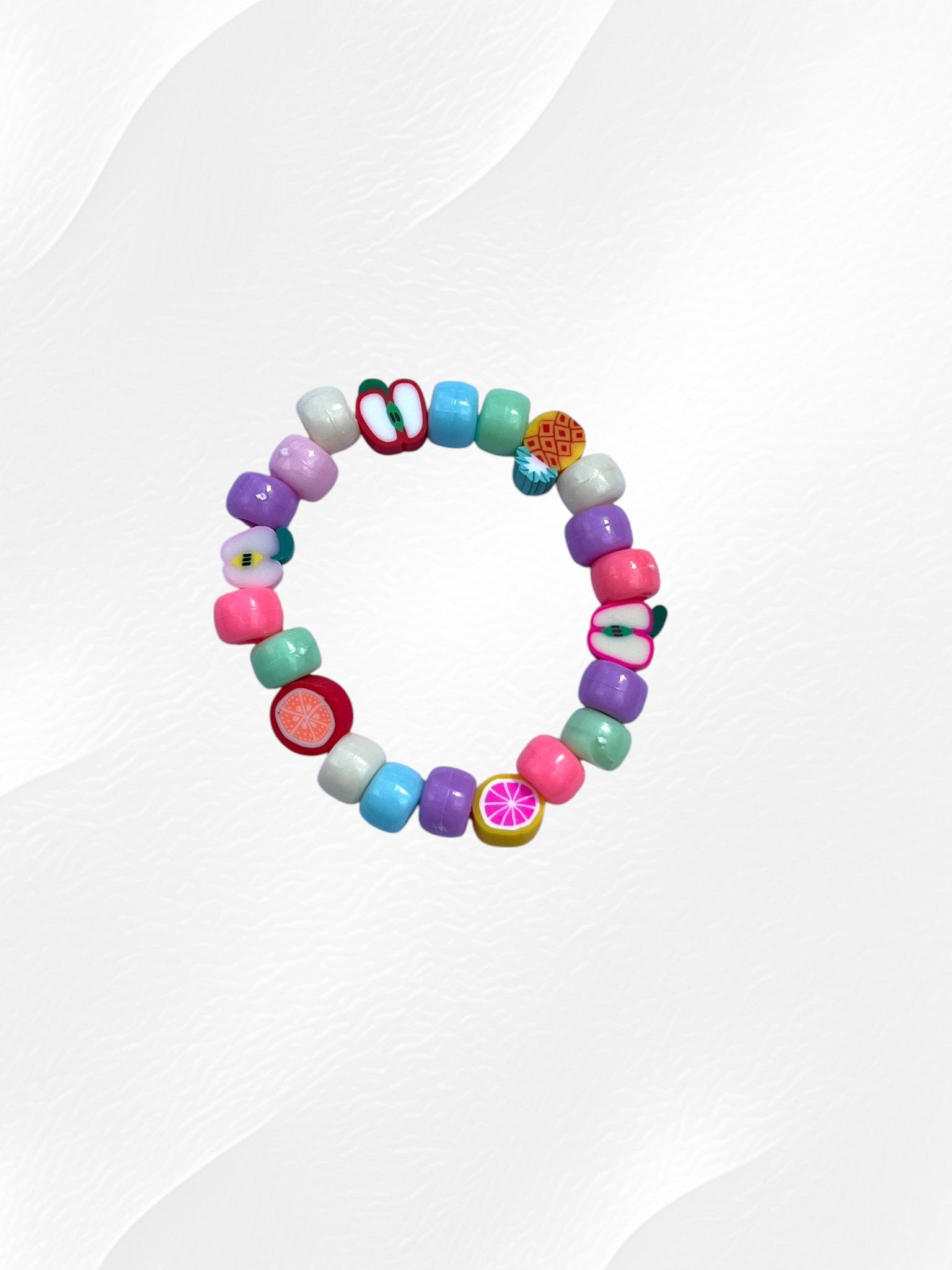 Bracelet pour enfant monté sur élastique.
Perles en acrylique multicolores pastel et perles fruits en argile polymère.