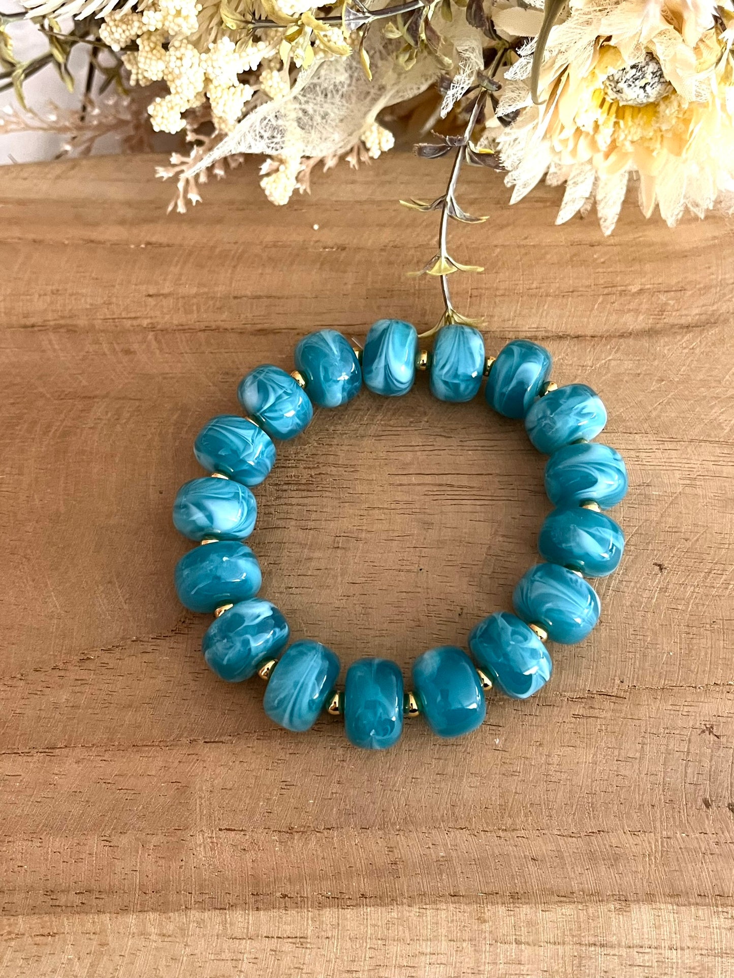 Bracelet élastique en perles résine couleur bleu sarcelle marbré.
Perles intercalaires en acier inoxydable doré de 4mm.
Bijou fantaisie fait main.