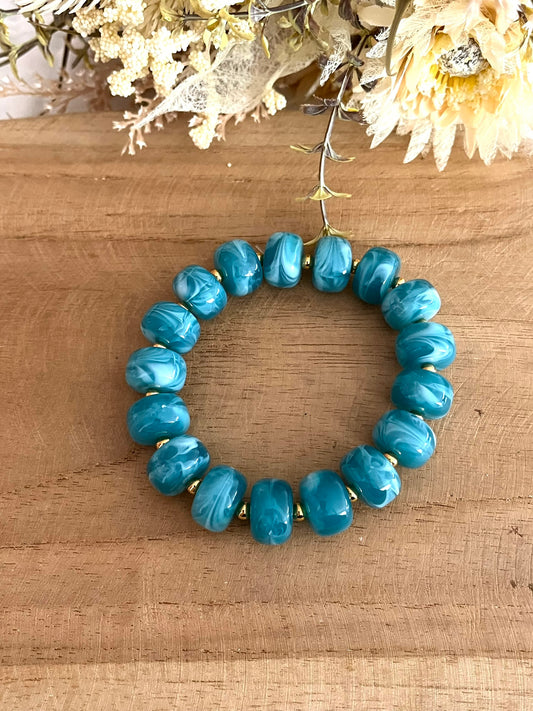 Bracelet élastique en perles résine couleur bleu sarcelle marbré.
Perles intercalaires en acier inoxydable doré de 4mm.
Bijou fantaisie fait main.