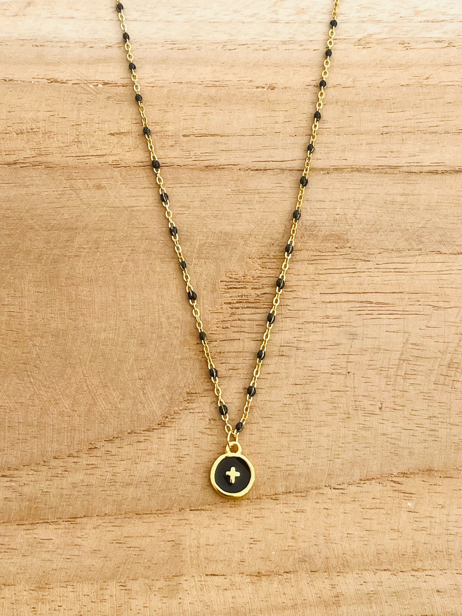 Collier fantaisie en acier inoxydable et résine epoxy doré et noir.
Pendentif rond avec une croix.
Bijou fantaisie fait main.