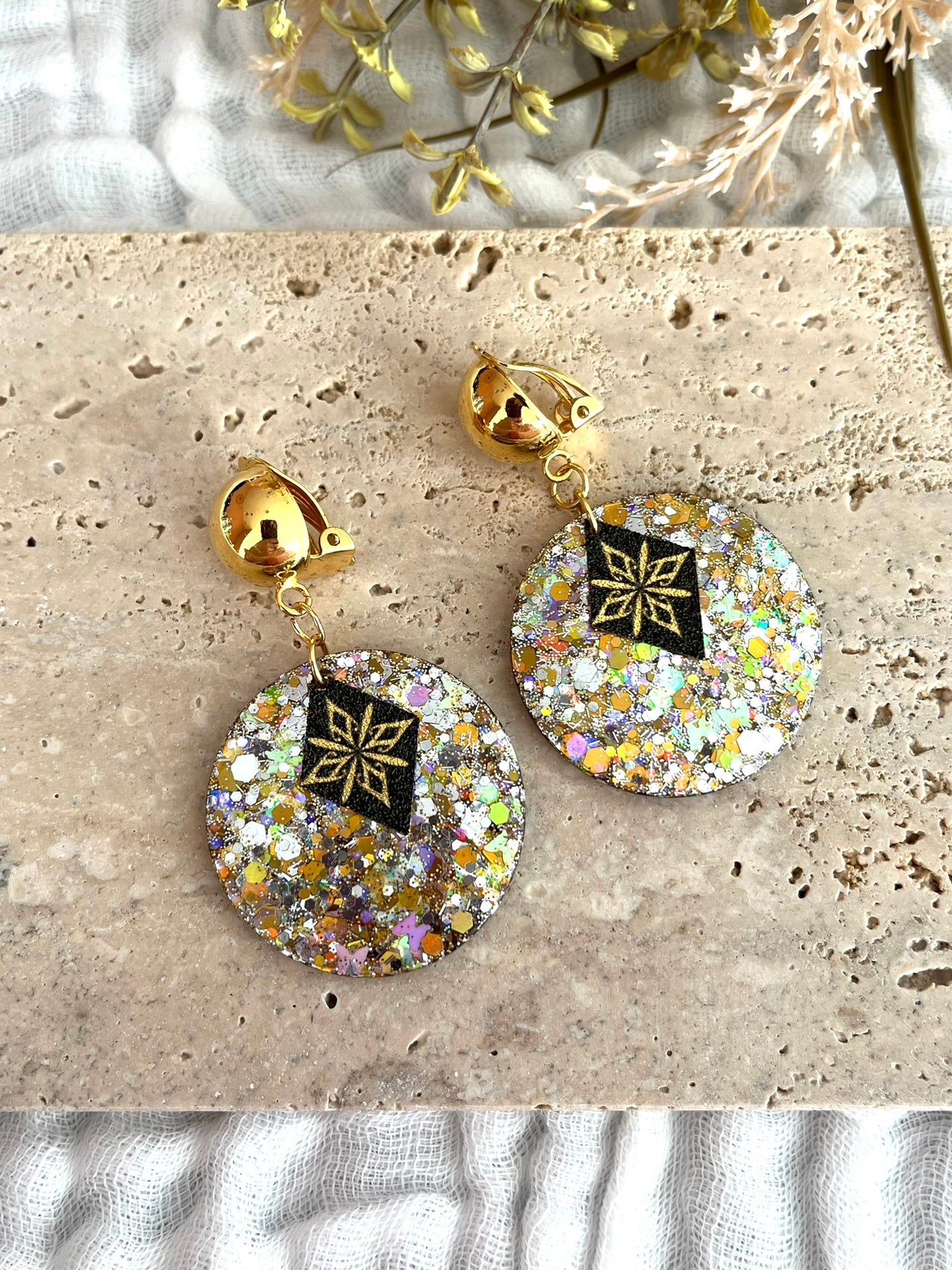 Boucles d'oreilles à clip fantaisie fait main.
CLips d'oreilles boule en laiton doré à l'or fin.
Pendentif rond en acrylique pailleté or et argent.
Sequin losange noir pailleté avec étoile polaire doré.
Bijou fantaisie fait main.