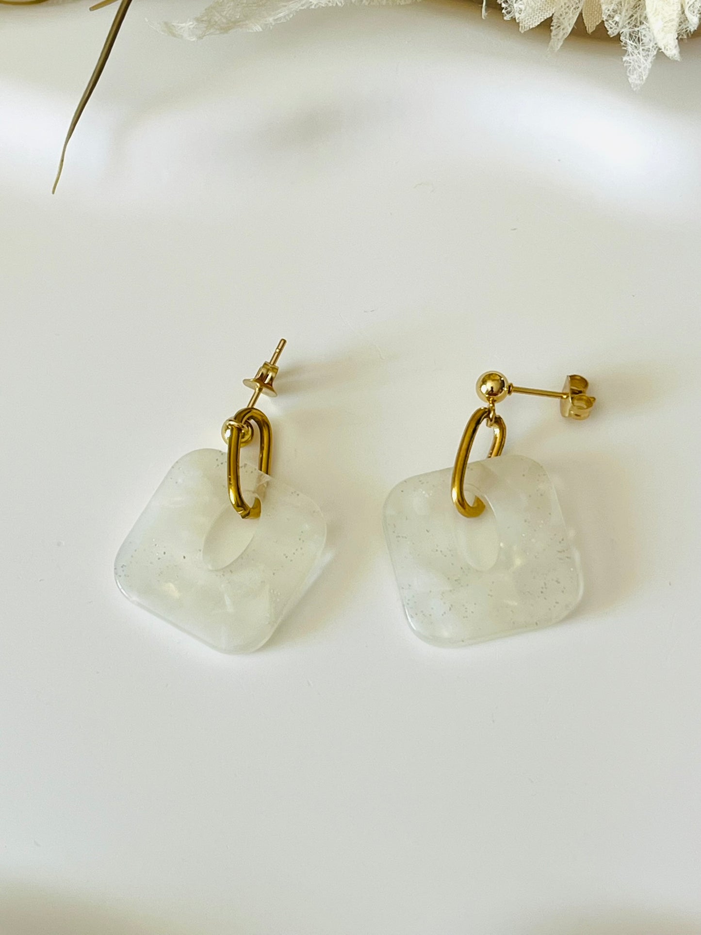 Boucles d'oreilles fantaisie fait main.
Clous d'oreilles en acier doré. Pendentif carré en acrylique marbré.
Bijou fait main.