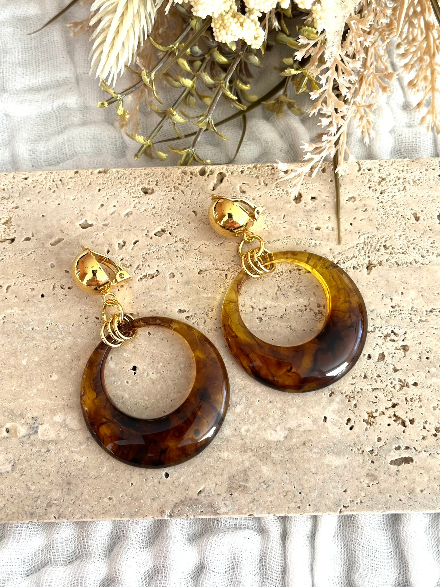 Boucles d'oreilles à clip fantaisie fait main.
Clips d'oreilles boule en laiton doré à l'or fin.
Pendentif en résine rond de couleur ambre.
Bijou fantaisie fait main.