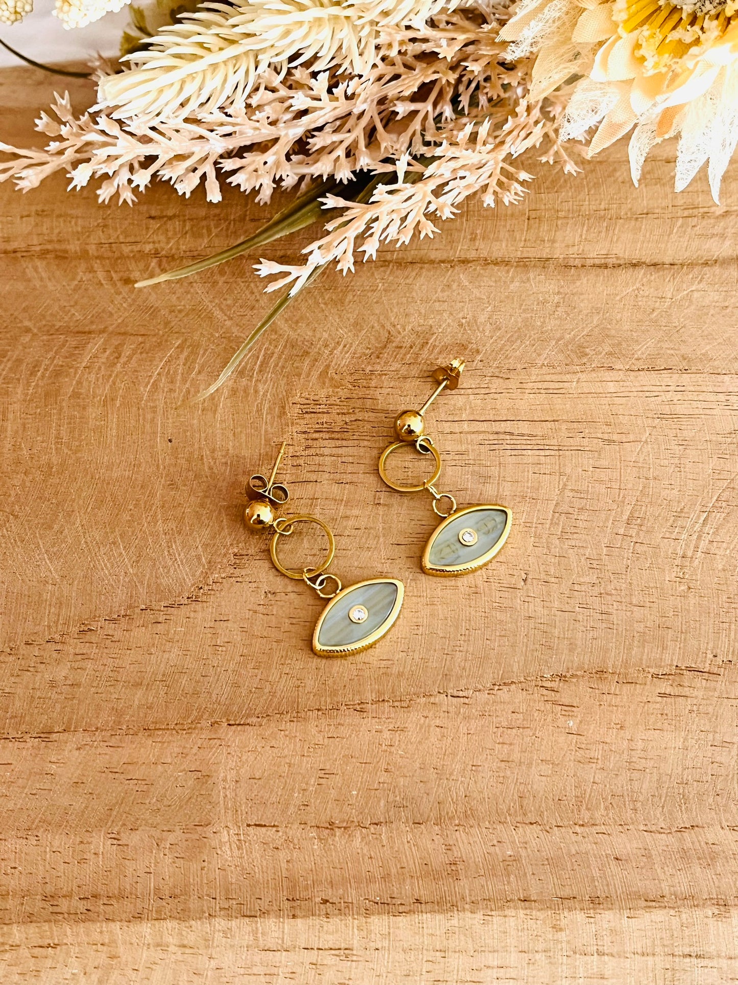 Boucles d'oreilles fantaisie fait main.
Clous d'oreilles en acier inoxydable doré, pendentif oeil gris nacré.
Bijou fantaisie fait main.