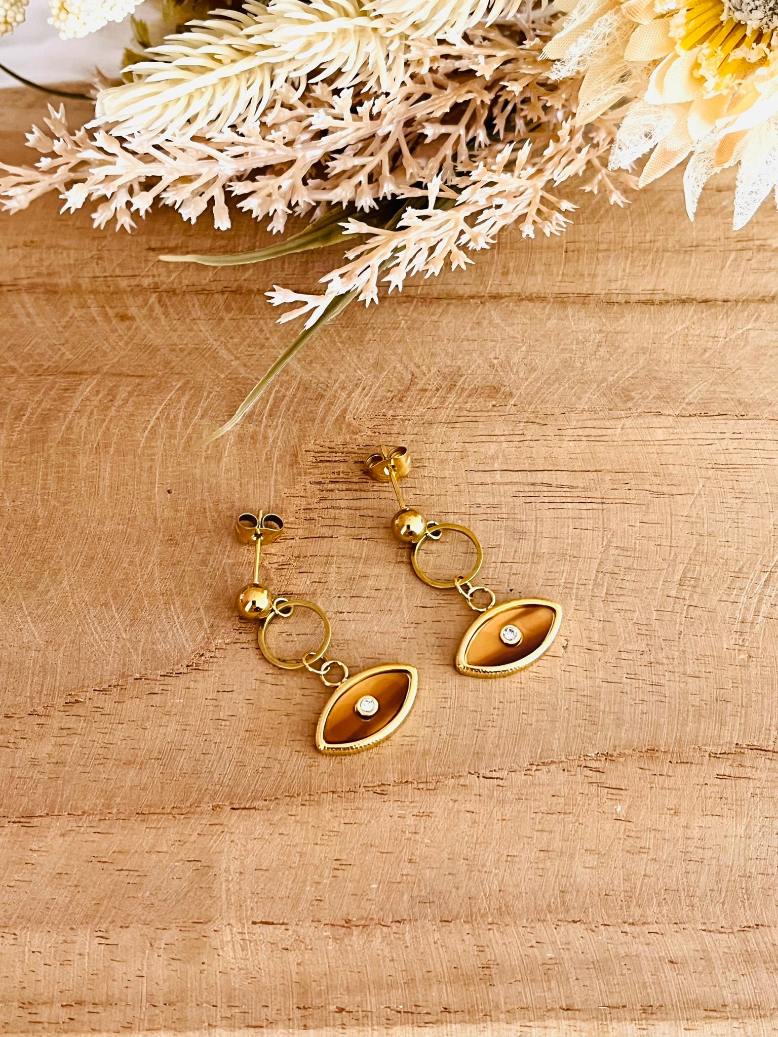 Boucles d'oreilles fantaisie fait main.
Clous d'oreilles en acier inoxydable doré, pendentif oeil marron ambre.
Bijou fantaisie fait main.