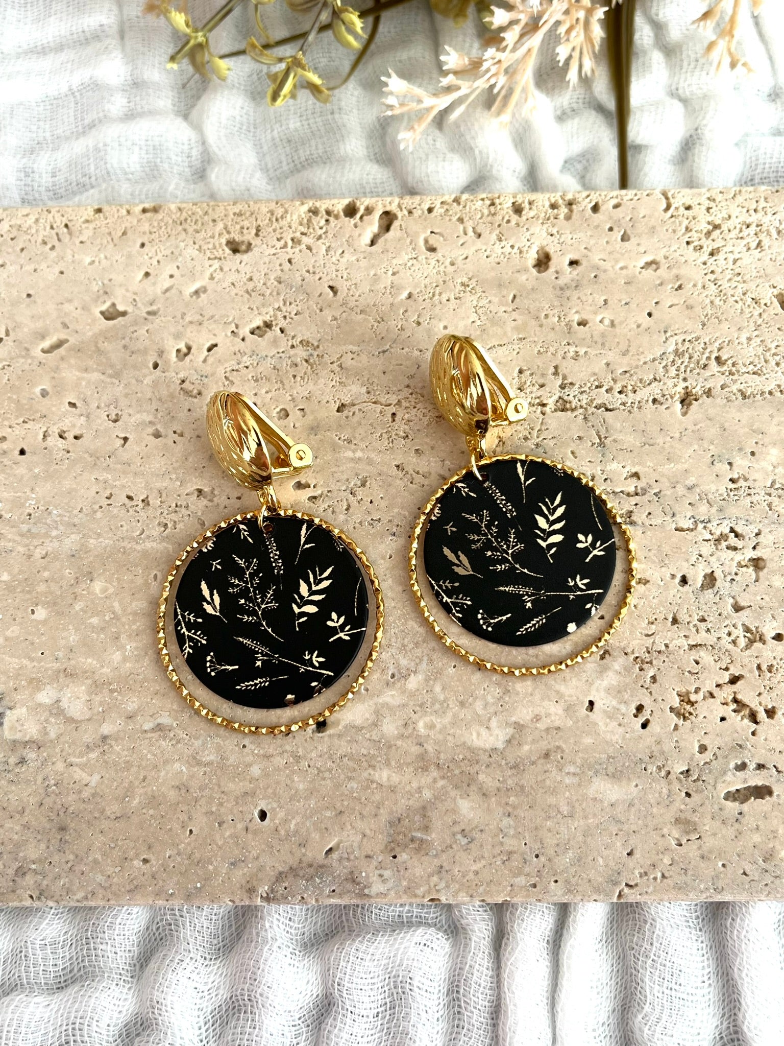 Boucles d'oreilles à clip fantaisie fait main.
Clip doré à l'or fin. Anneaux ciselés en acier inoxydable doré. Pendentifs ronds noir imprimé feuilles doré.
Bijou fantaisie fait main