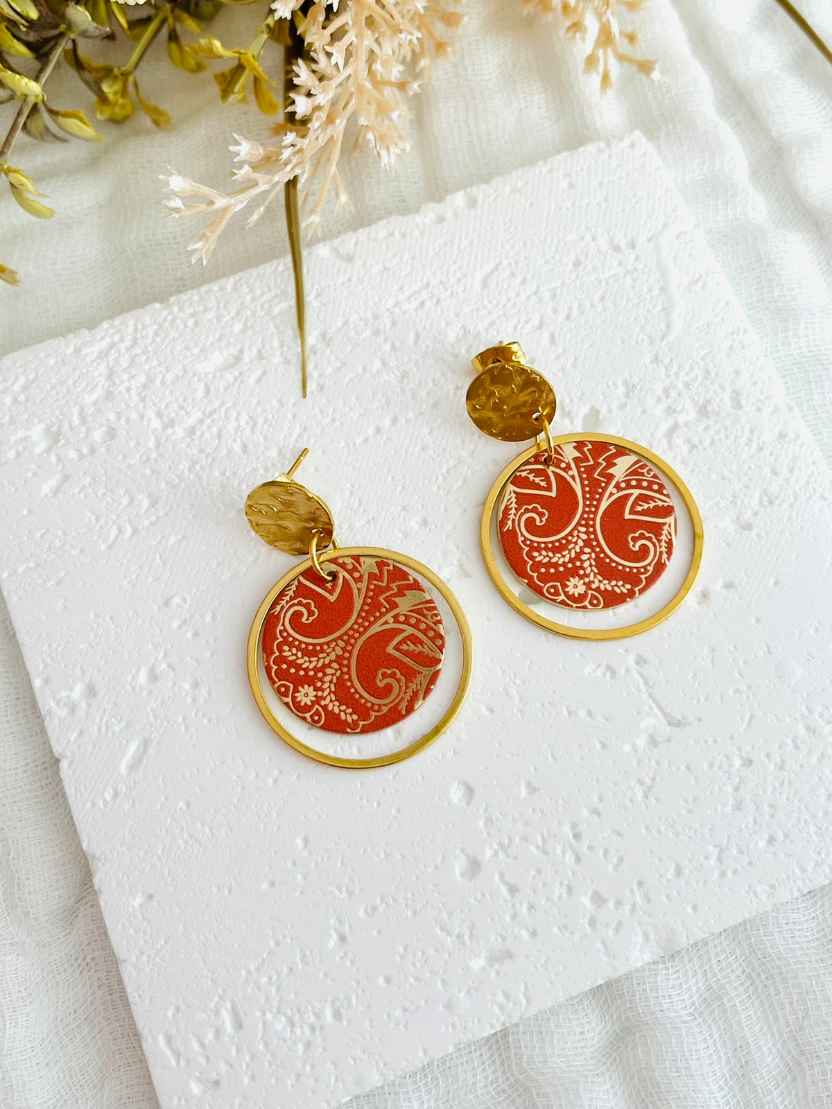 Boucles d'oreilles fantaisie fait main.
Clous d'oreilles ronds martelés doré en acier inox; annaux fermés en acier inox doré, pendentif rond motif bandana, cachemire terracotta et or.
Bijou fantaisie fait main.