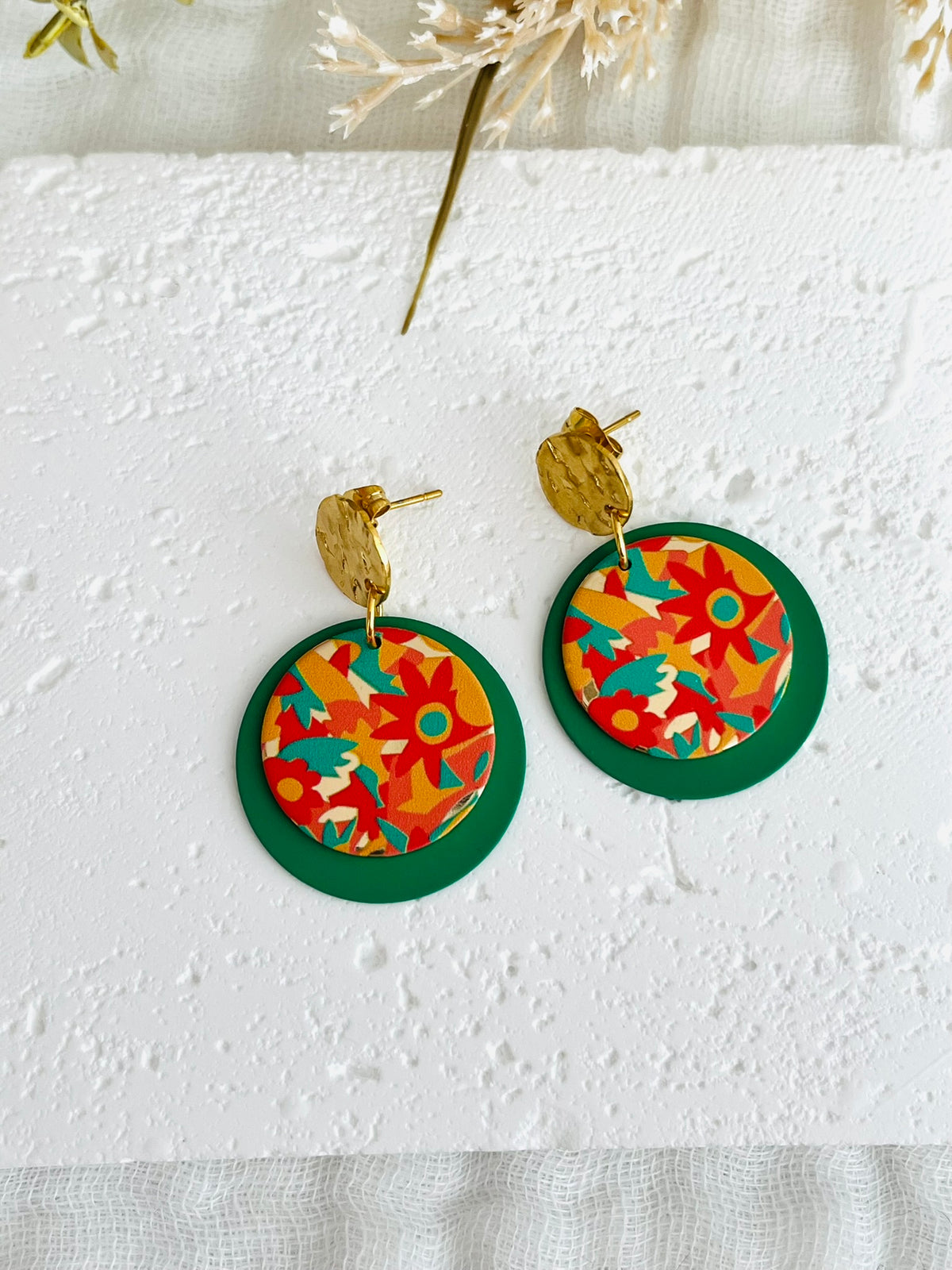 Boucles d'oreilles fantaisie fait main.
Clous d'oreilles ronds martelés en acier inox doré.
Sequins ronds vert, pendentifs imprimés fleurs orange, vert, jaune.
Bijou fantaisie fait main.