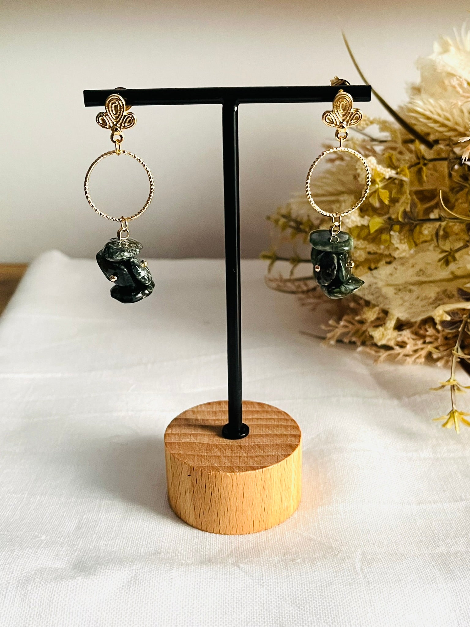 Boucles d'oreilles fantaisie fait main.
Clous d'oreilles feuille en laiton plaqué or 18k. Anneaux ciselés de 15mm en laiton plaqué or 18k. Grappe de perles en séraphinite.
Bijou fantaisie fait main.