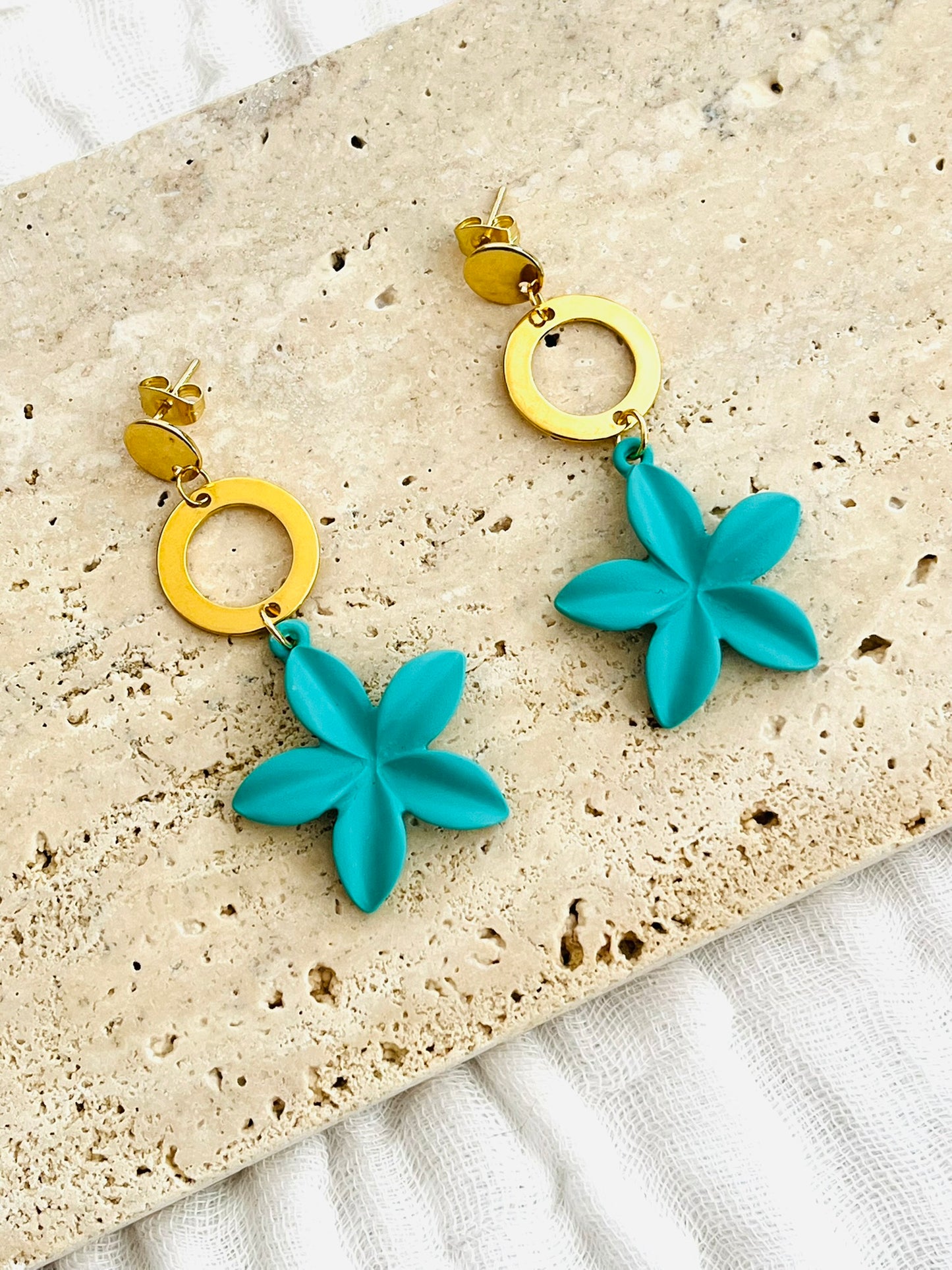 Boucles d'oreilles fantaisie fait main.
Clous d'oreilles en acier inox doré; connecteurs ronds en acier inox doré, pendentif fleur de frangipanier turquoise.
Bijou fait main.