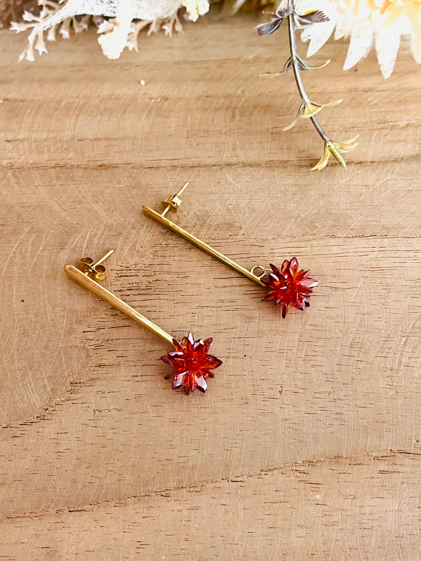 Boucles d'oreilles fantaisie fait main.
Clous d'oreilles longue barre en acier inoxydable doré. Pendentif fleur étoilée en verre cristal de couleur rouille.
Bijou fantaisie fait main.
