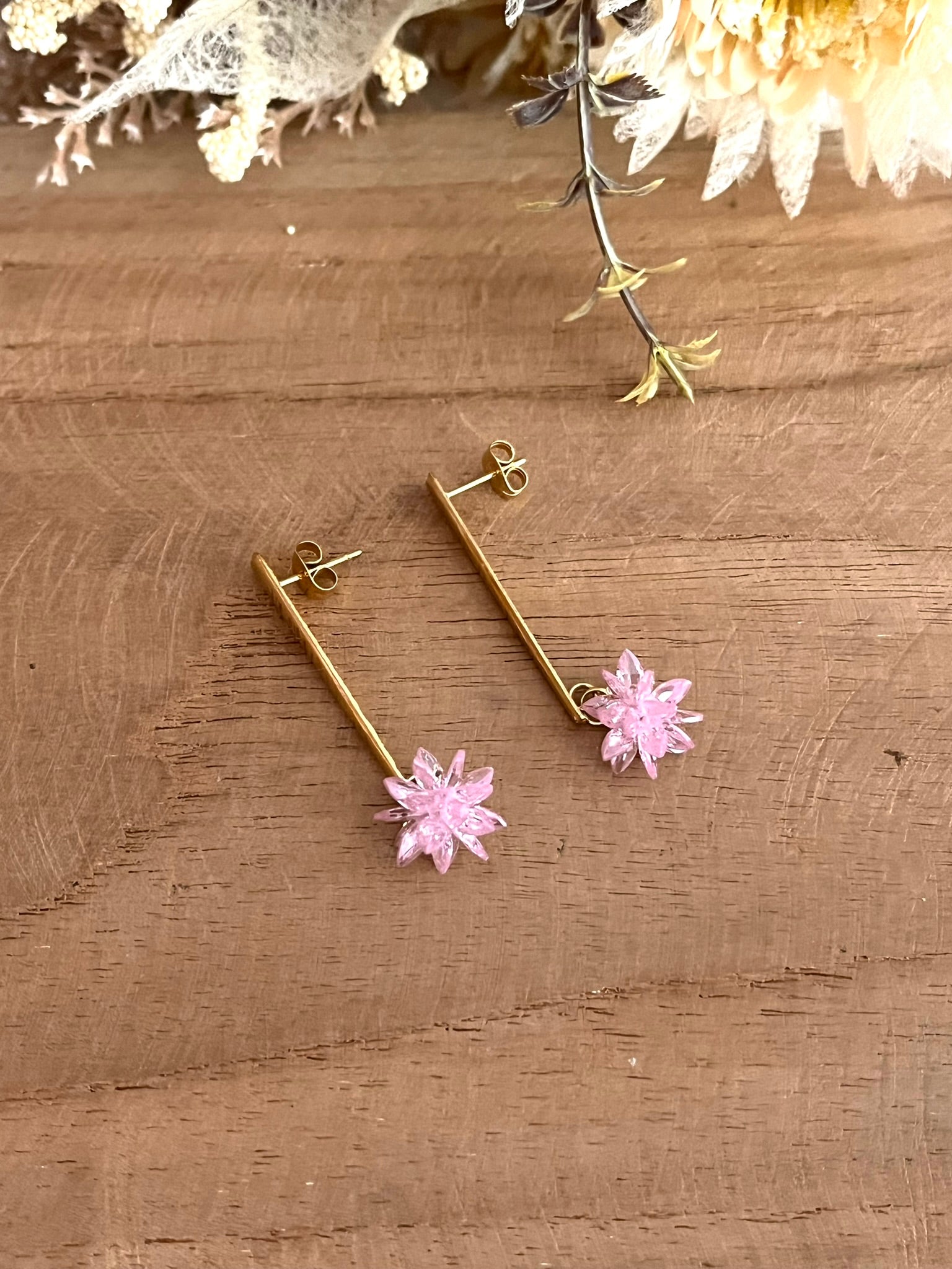 Boucles d'oreilles fantaisie fait main.
Clous d'oreilles longue barre en acier inoxydable doré. Pendentif fleur étoilée en verre cristal de couleur rose.
Bijou fantaisie fait main.