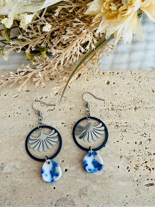 Boucles d'oreilles fantaisie fait main.
Crochets en acier inox, anneaux bleu marine, estampe éventail en acier inox, goutte en acrylique blanc marbré bleu.
Bijou fantaisie fait main.