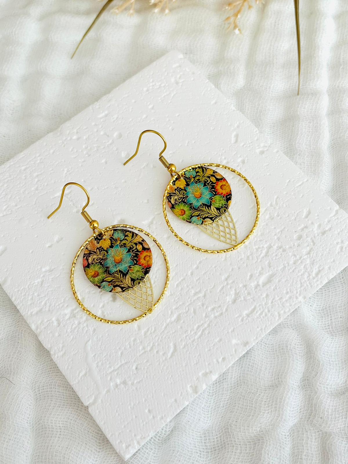 Boucles d'oreilles fantaisie fait main.
Crochets d'oreilles en acier inoxydable doré; anneaux fermés ciselés en laiton or 18k; estampe navette filigranée doré, sequin ronds pailleté motif fleurs noir, vert, bleu.
Bijou fait main.
