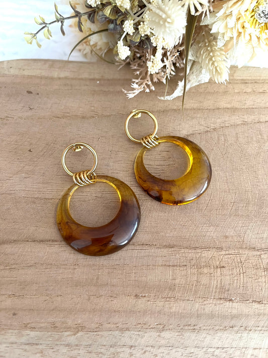 Boucles d'oreilles fantaisie fait main.
Clous d'oreilles cercle en acier inoxydable doré avec pendentif cercle en résine translucide marron ambré.
Bijou fantaisie fait main.