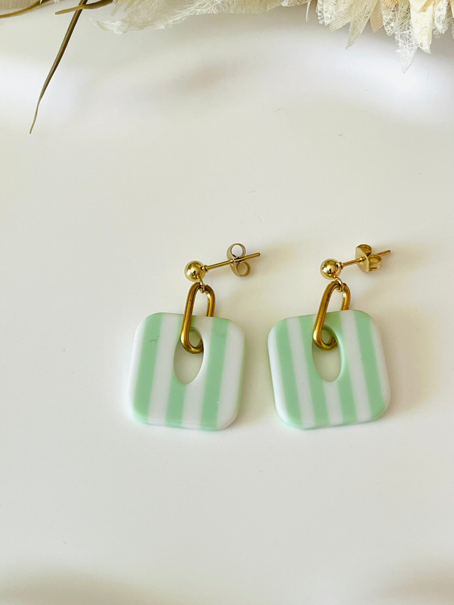 Boucles d'oreilles fantaisie fait main.
Clous d'oreilles en acier inoxydable doré. Pendentif carré en acrylique rayés.
Bijou fait main