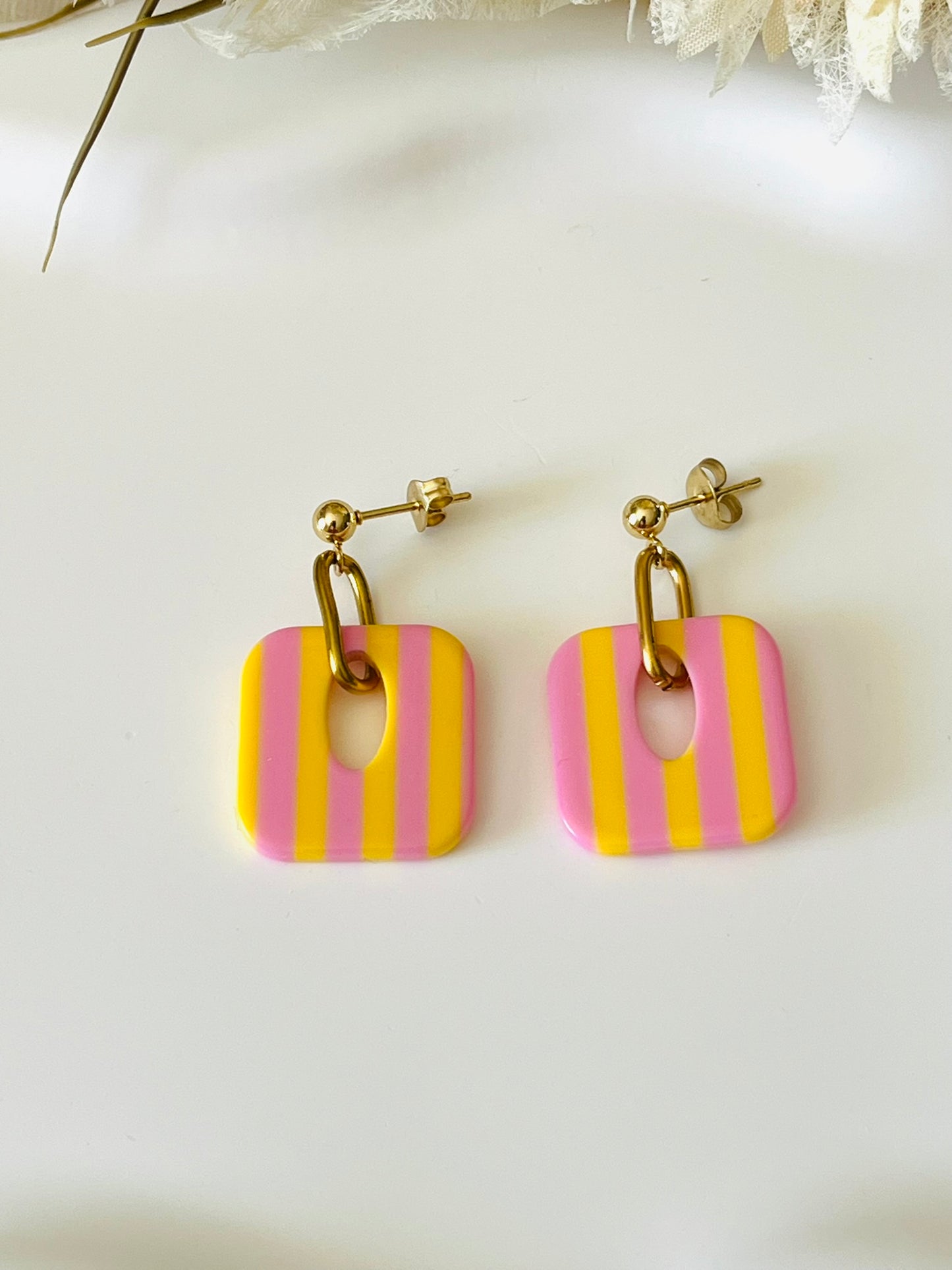 Boucles d'oreilles fantaisie fait main.
Clous d'oreilles en acier inoxydable doré. Pendentif carré en acrylique rayés.
Bijou fait main