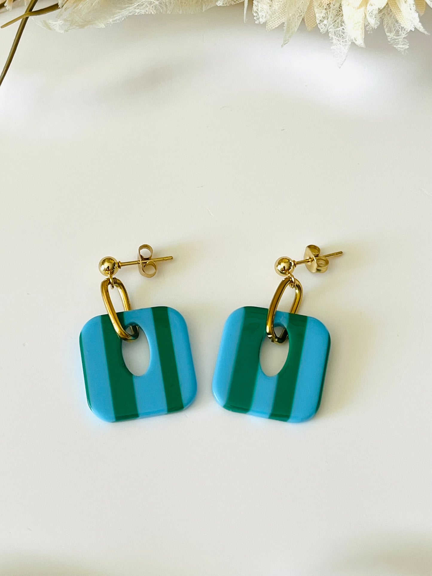 Boucles d'oreilles fantaisie fait main.
Clous d'oreilles en acier inoxydable doré. Pendentif carré en acrylique rayés.
Bijou fait main