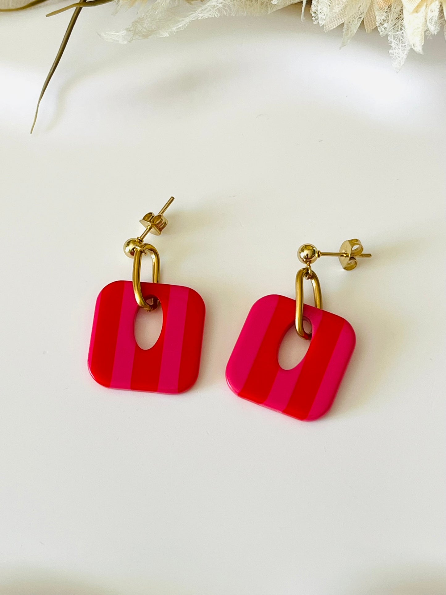 Boucles d'oreilles fantaisie fait main.
Clous d'oreilles en acier inoxydable doré. Pendentif carré en acrylique rayés.
Bijou fait main