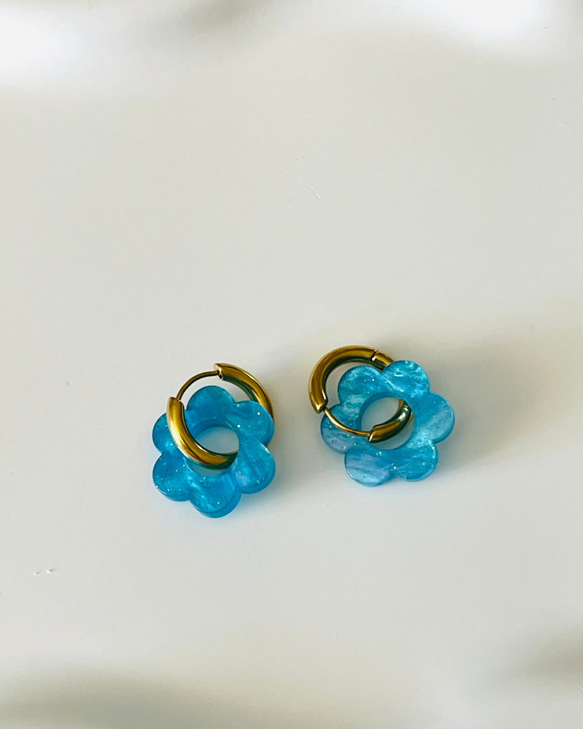 Boucles d'oreilles créoles adaptées pour les enfants à partir de 6 ans.
Créoles en acier inoxydable doré de 15mm.
Petites fleurs bleu marbré avec paillettes en acrylique.