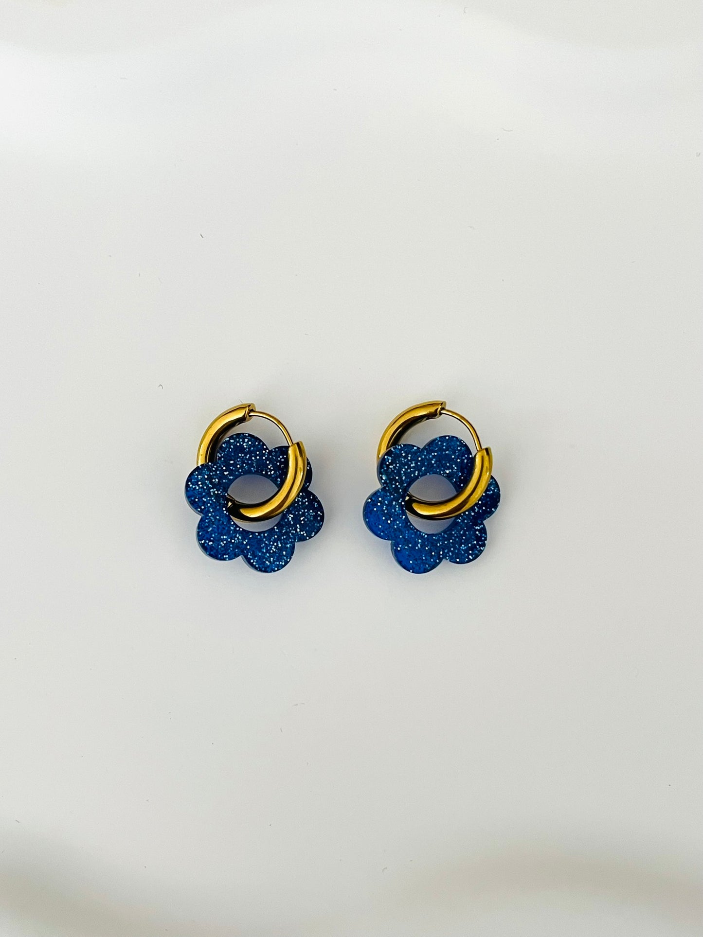 Boucles d'oreilles créoles adaptées pour les enfants à partir de 6 ans.
Créoles en acier inoxydable doré de 15mm.
Petites fleurs bleu pailleté en acrylique.
