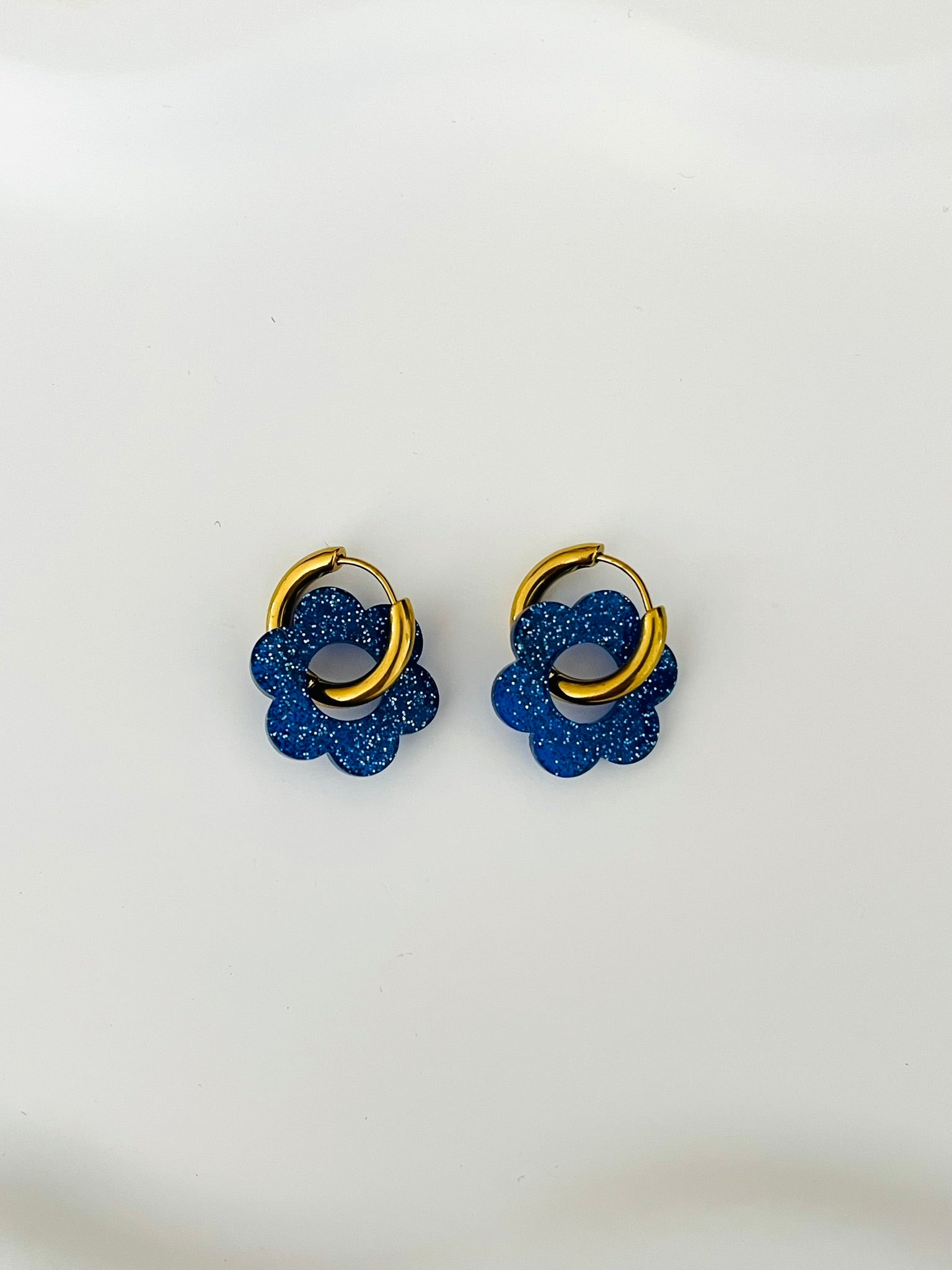Boucles d'oreilles créoles adaptées pour les enfants à partir de 6 ans.
Créoles en acier inoxydable doré de 15mm.
Petites fleurs bleu pailleté en acrylique.
