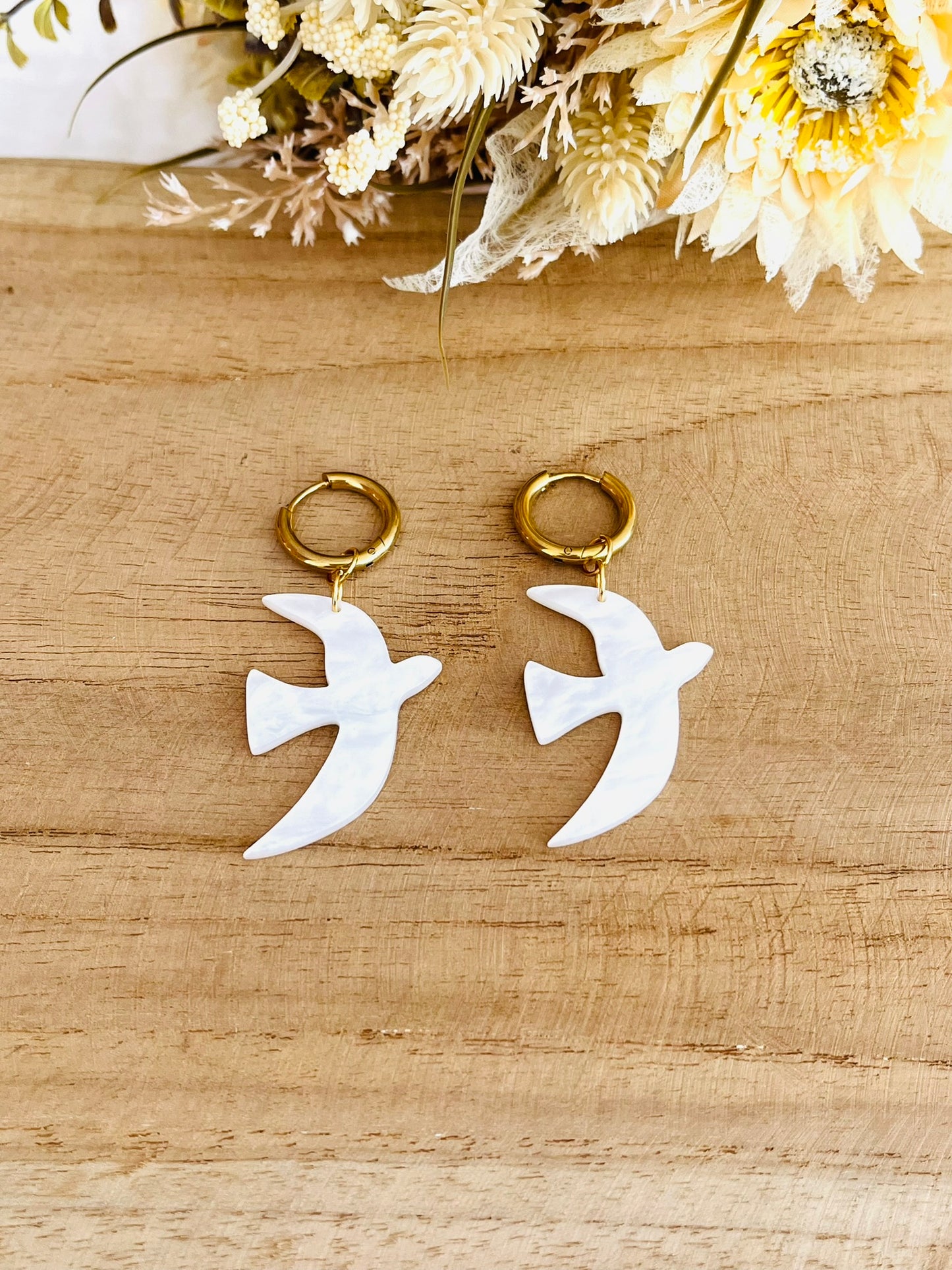 Boucles d'oreilles fantaisie fait main.
Créoles en acier inoxydable doré. Pendentifs hirondelle en acrylique blanc nacré.