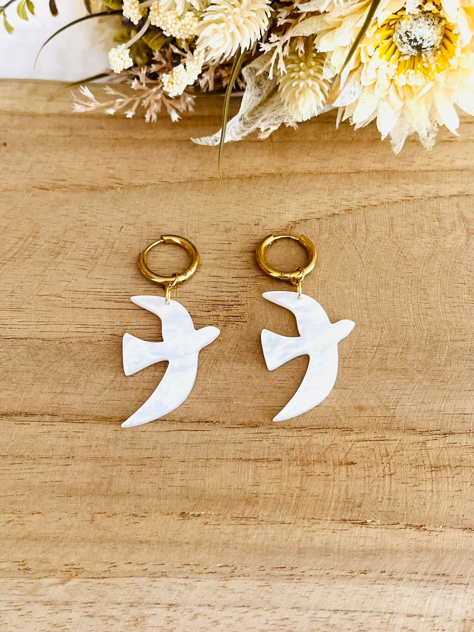 Boucles d'oreilles fantaisie fait main.
Créoles en acier inoxydable doré. Pendentifs hirondelle en acrylique blanc nacré.