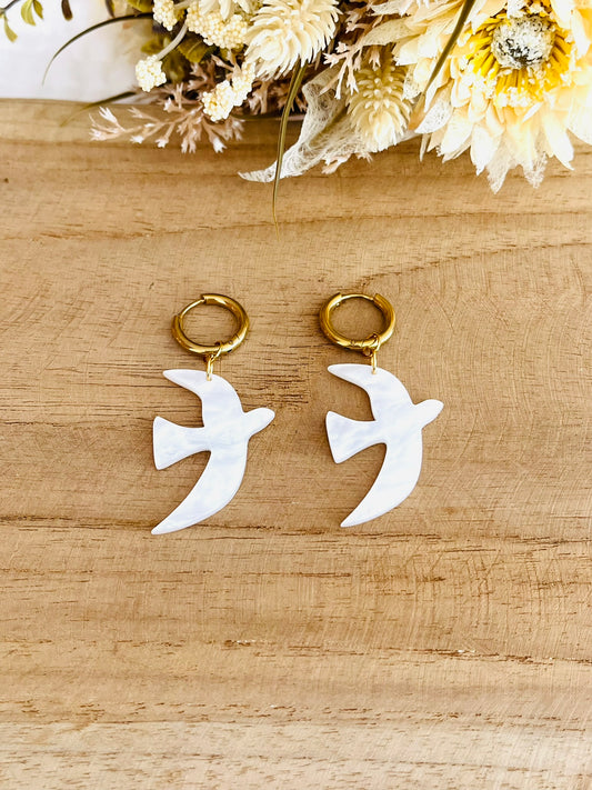 Boucles d'oreilles fantaisie fait main.
Créoles en acier inoxydable doré. Pendentifs hirondelle en acrylique blanc nacré.