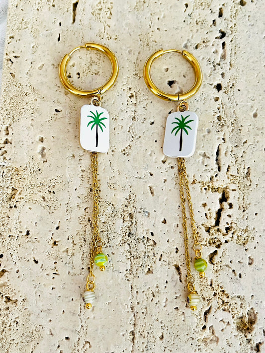 Boucles d'oreilles fantaisie fait main.
Créoles en acier doré.
Pendentif rectangle blanc orné d'un palmier vert.
2 Chainettes de longueur asymétrique réhaussées de perles millefiori dans les tons vert.
Bijou fait main