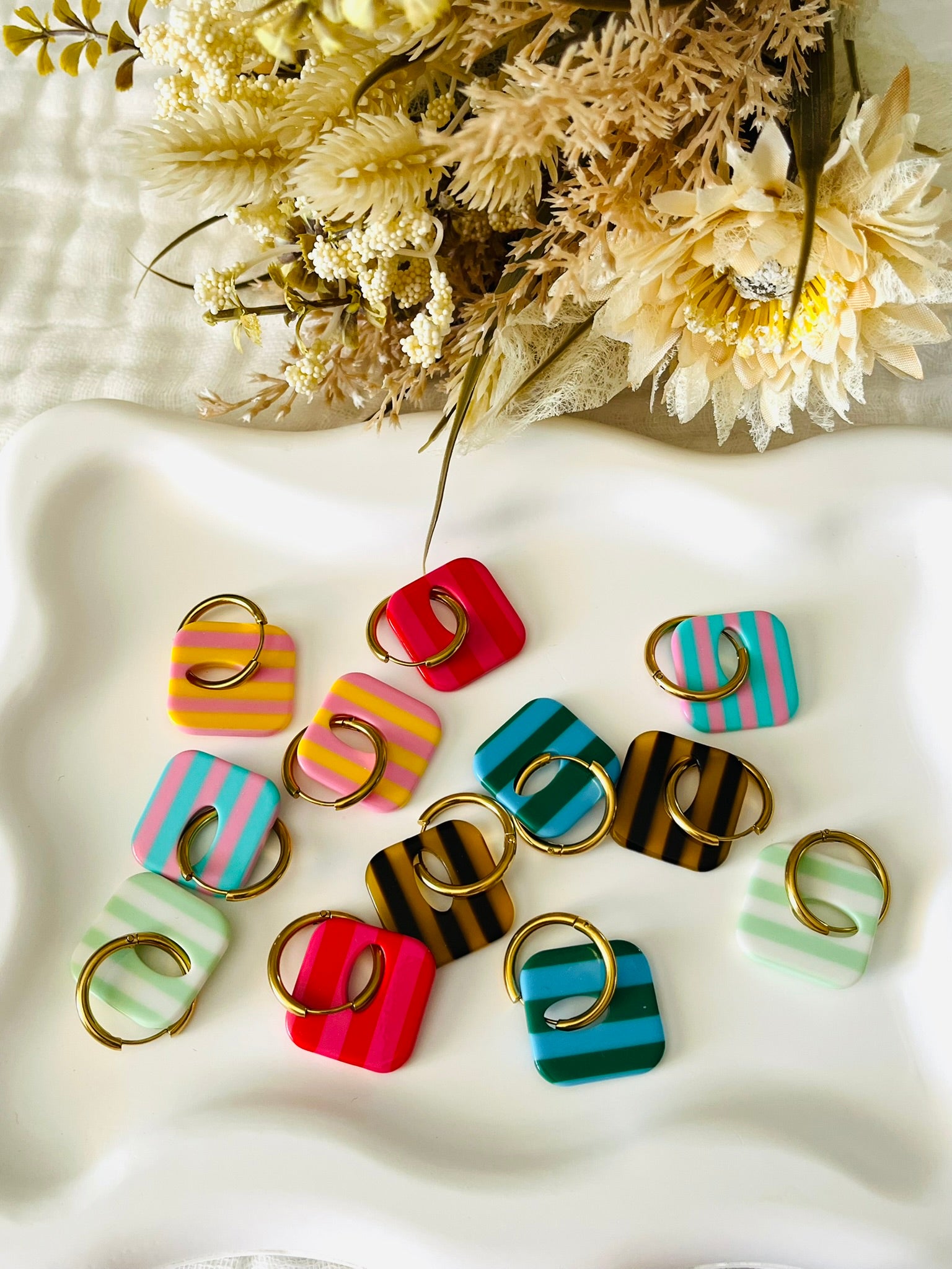 Boucles d'oreilles fantaisie fait main.
Créoles en acier inoxydable avec pampilles interchangeables.
Pampilles carrées bicolores rayées.
Bijou fantaisie fait main.