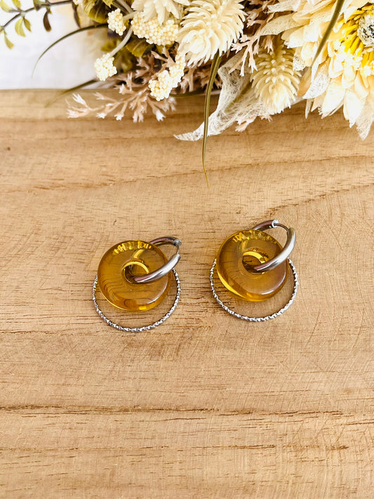 Boucles d'oreilles fantaisie fait main.
Créoles rondes en acier inoxydable couleur argent avec pendentif donut en résine jaune translucide.