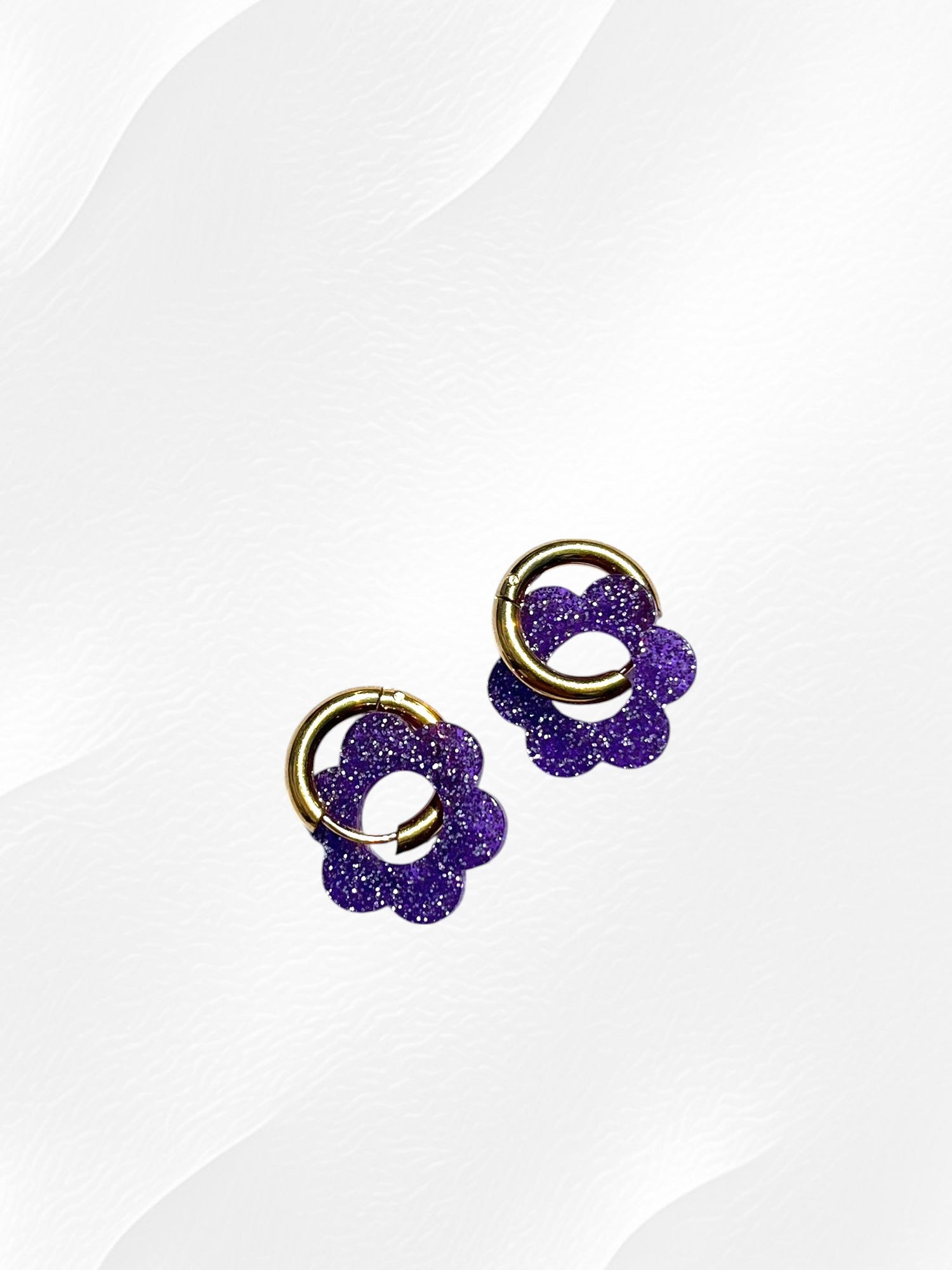 Boucles d'oreilles créoles adaptées pour les enfants à partir de 6 ans.
Créoles en acier inoxydable doré de 15mm.
Petites fleurs violet pailleté en acrylique.