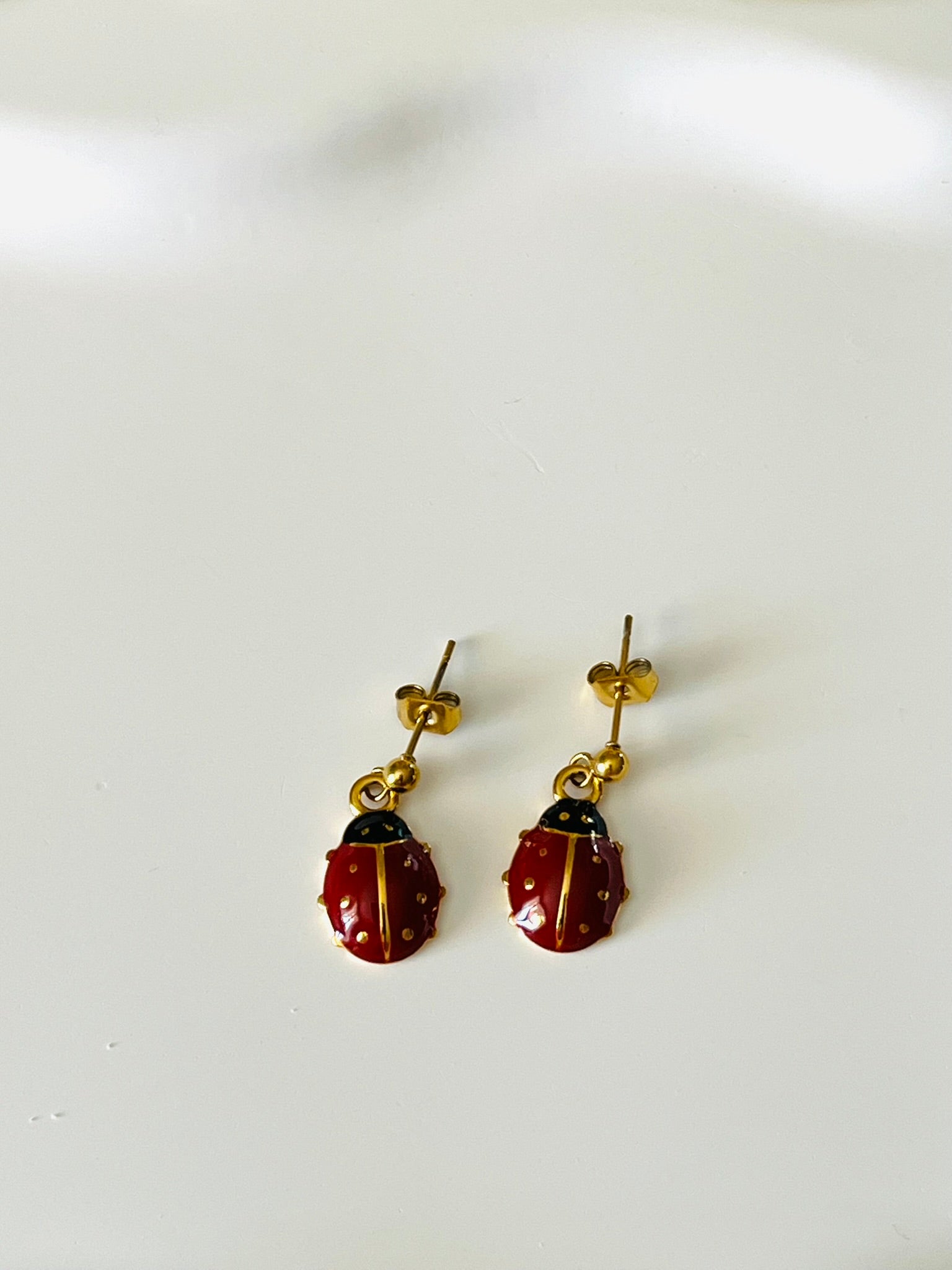 Boucles d'oreilles à clous adaptées pour les enfants à partir de 6 ans.
Clous d'oreilles en acier inoxydable doré.
Pendentif coccinelle en acier inox doré et résine epoxy rouge.