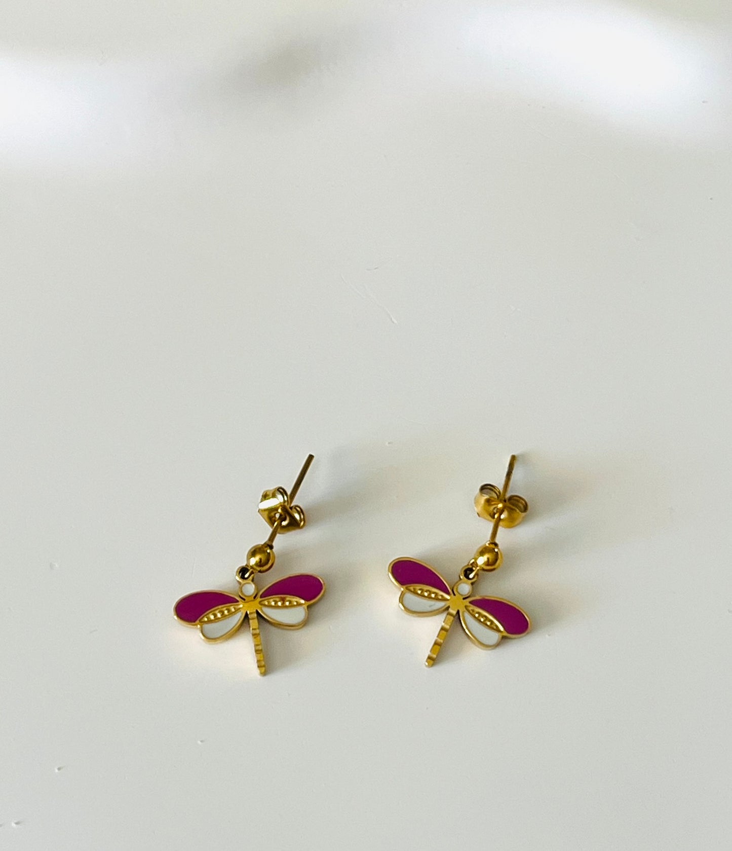 Boucles d'oreilles à clous adaptées pour les enfants à partir de 6 ans.
Clous d'oreilles en acier inoxydable doré.
Pendentif libellule en acier inox doré et résine epoxy violet et blanc.