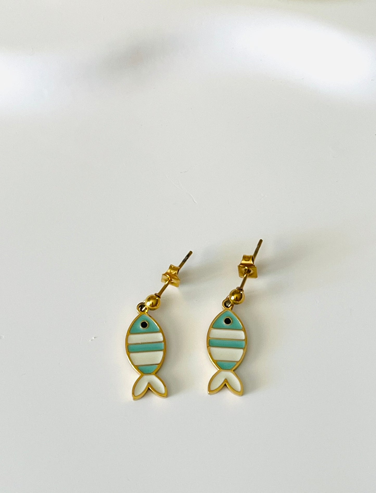 Boucles d'oreilles à clous adaptées pour les enfants à partir de 6 ans.
Clous d'oreilles en acier inoxydable doré.
Pendentif poisson en acier inox doré et résine epoxy blanc et turquoise