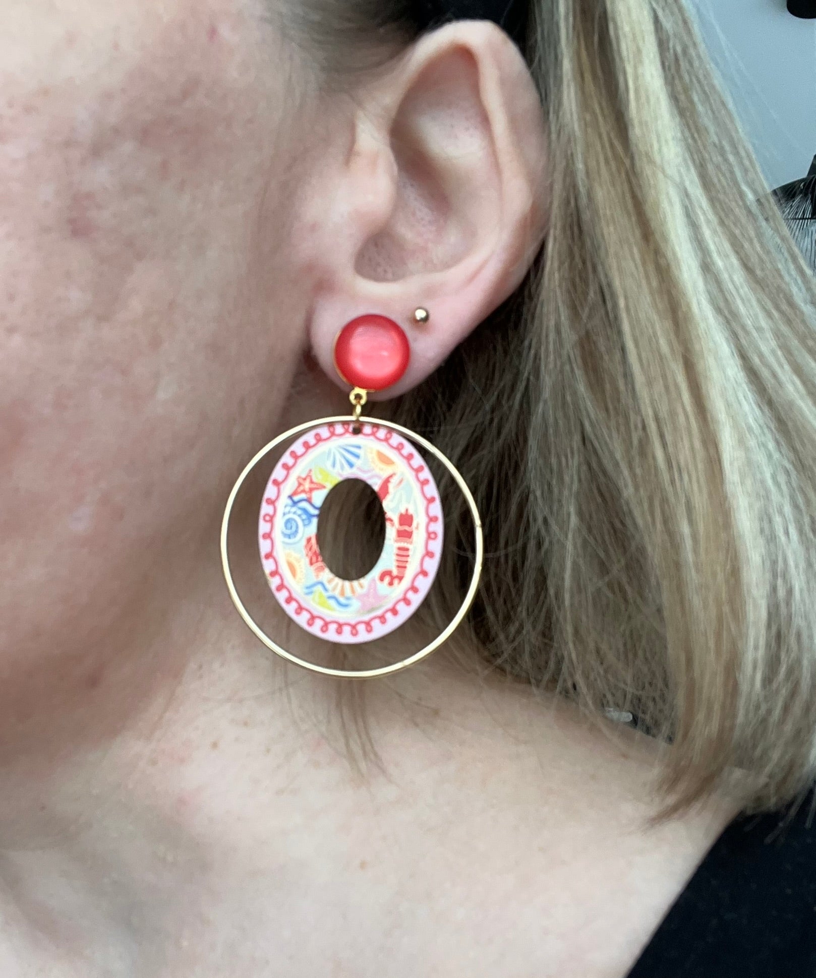 Boucles d'oreilles fantaisie fait main.
Clous d'oreilles en laiton doré à l'or fin rehaussé d'un cabochon rouge.
Anneaux fermés en laiton plaqué or 18k.
Pendentifs ronds imprimé homard, étoile de mer, coquillage, soleil.
Bijou fait main.